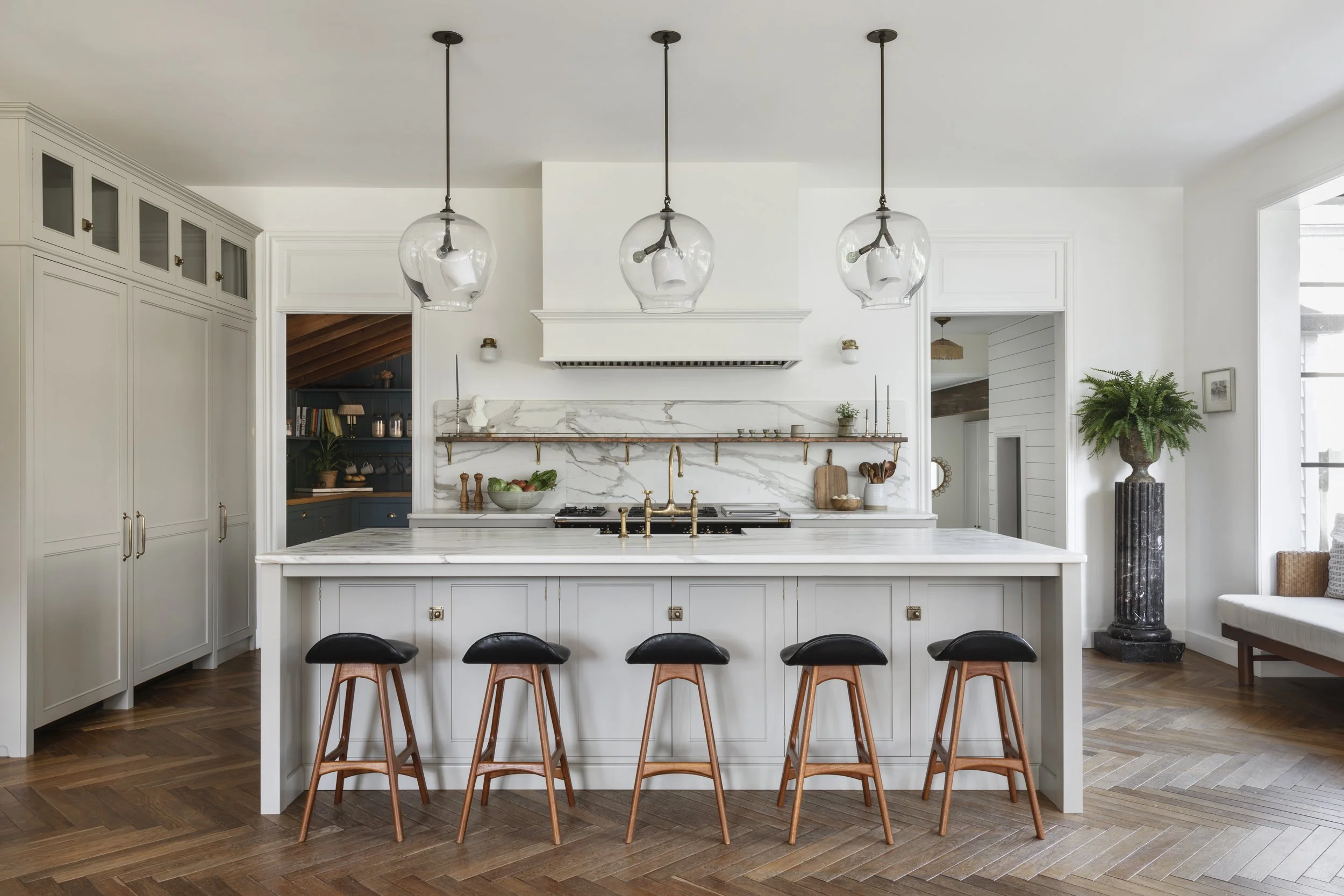 Modern kitchen with white cabinets, a marble island, pendant lights, and bar stools.