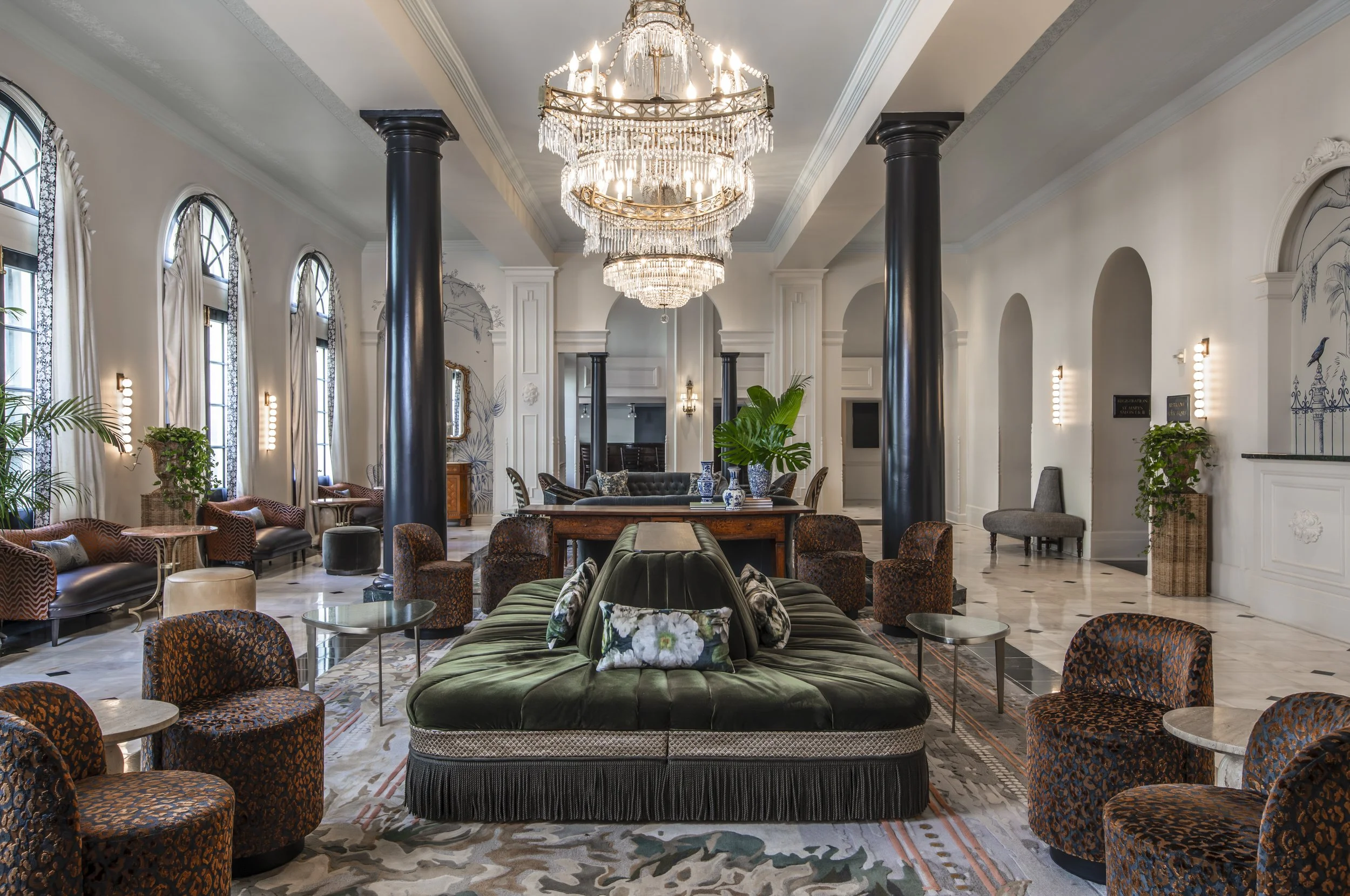 Lobby with crystal chandelier, columns and round tufted settee at the Bourbon Orleans