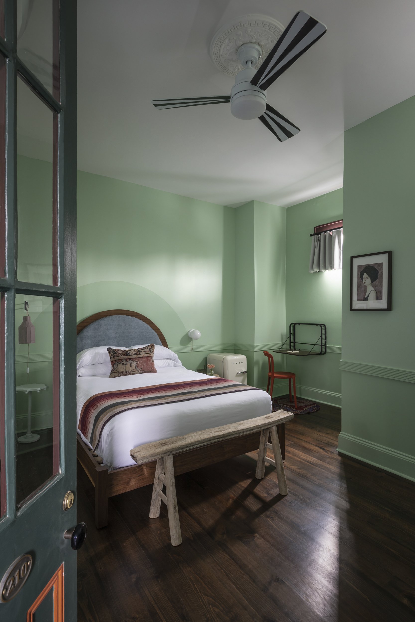 Teal door with brass 210 plate opening onto a mint green guestroom at the Frenchmen
