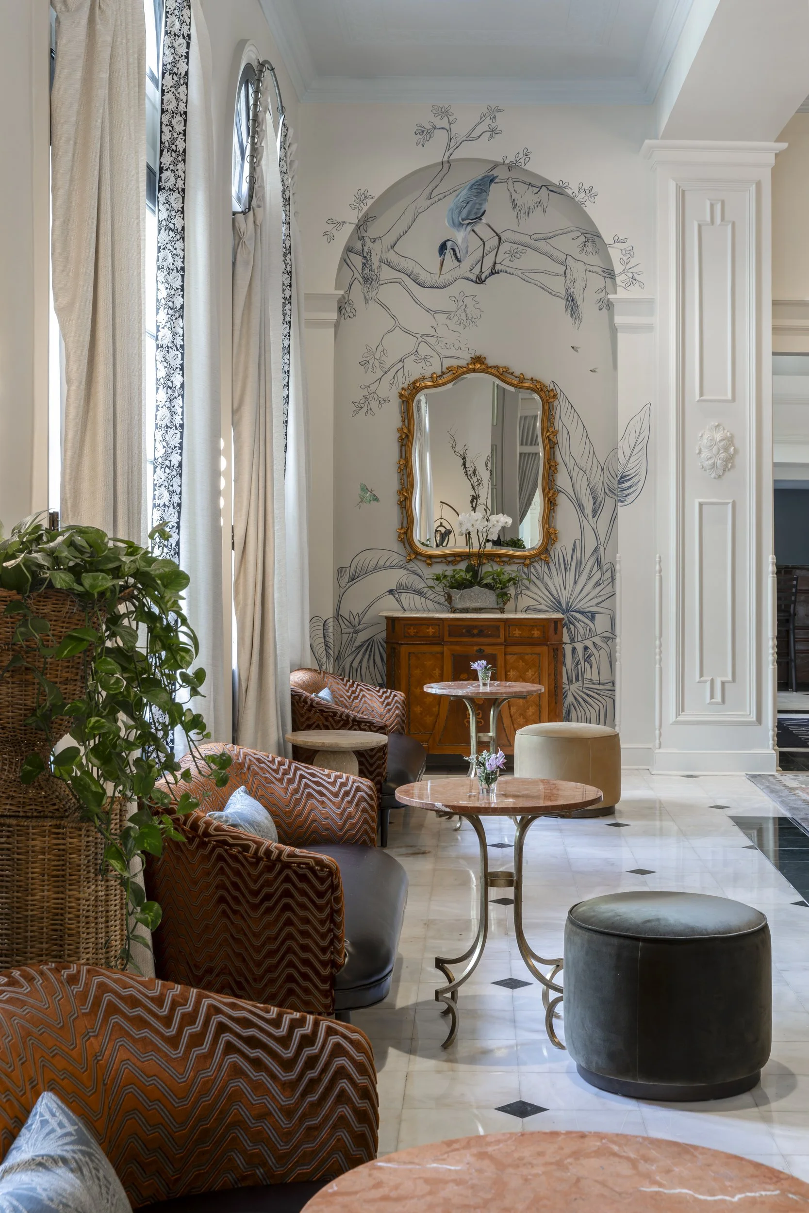 Lobby seating with wall mural painted by Annie Moran gold mirror and rattan armchairs at the Bourbon Orleans