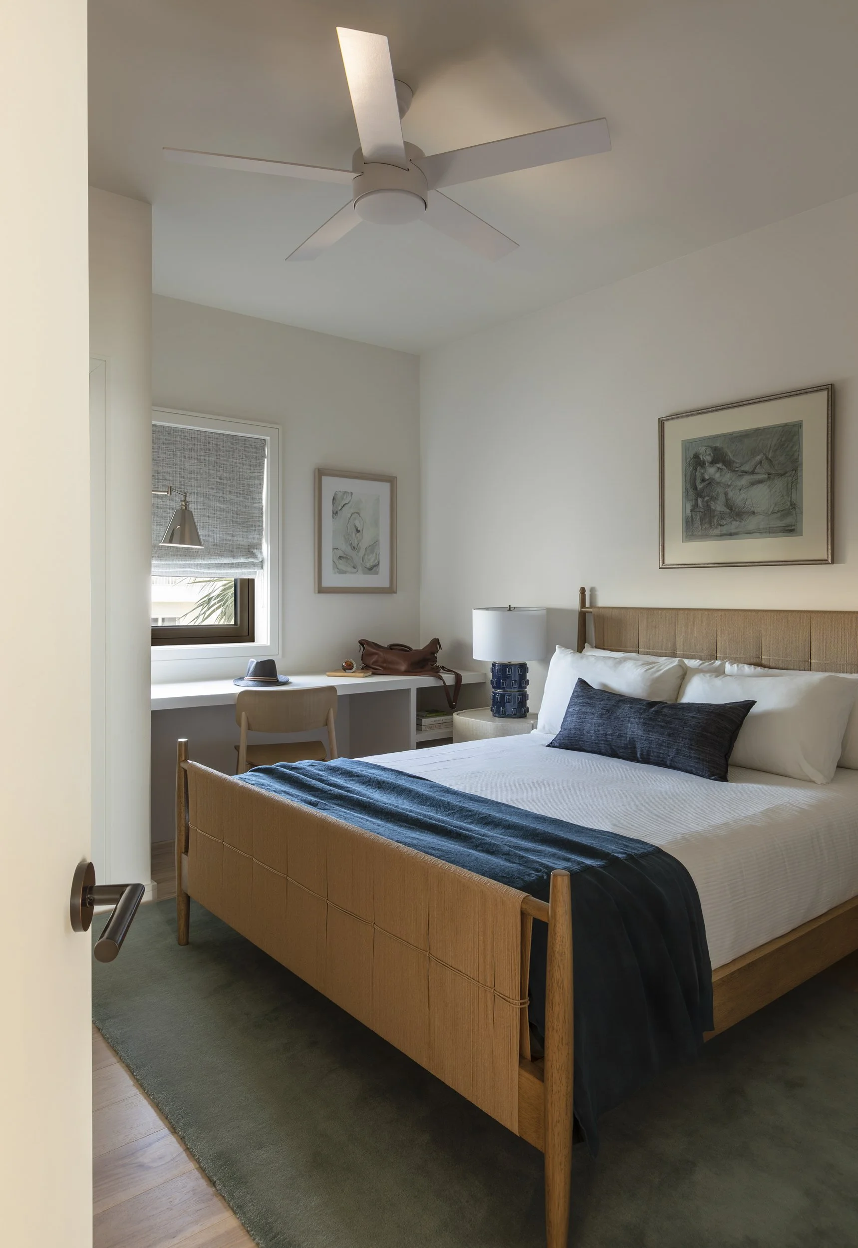 Coastal guestroom with wood bed frame and navy throw in ocean light at the Seaside