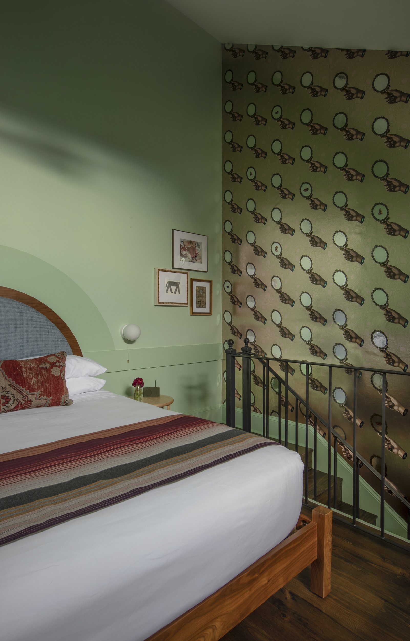 Mezzanine bed with iron railing against spyglass-patterned wallpaper at the Frenchmen
