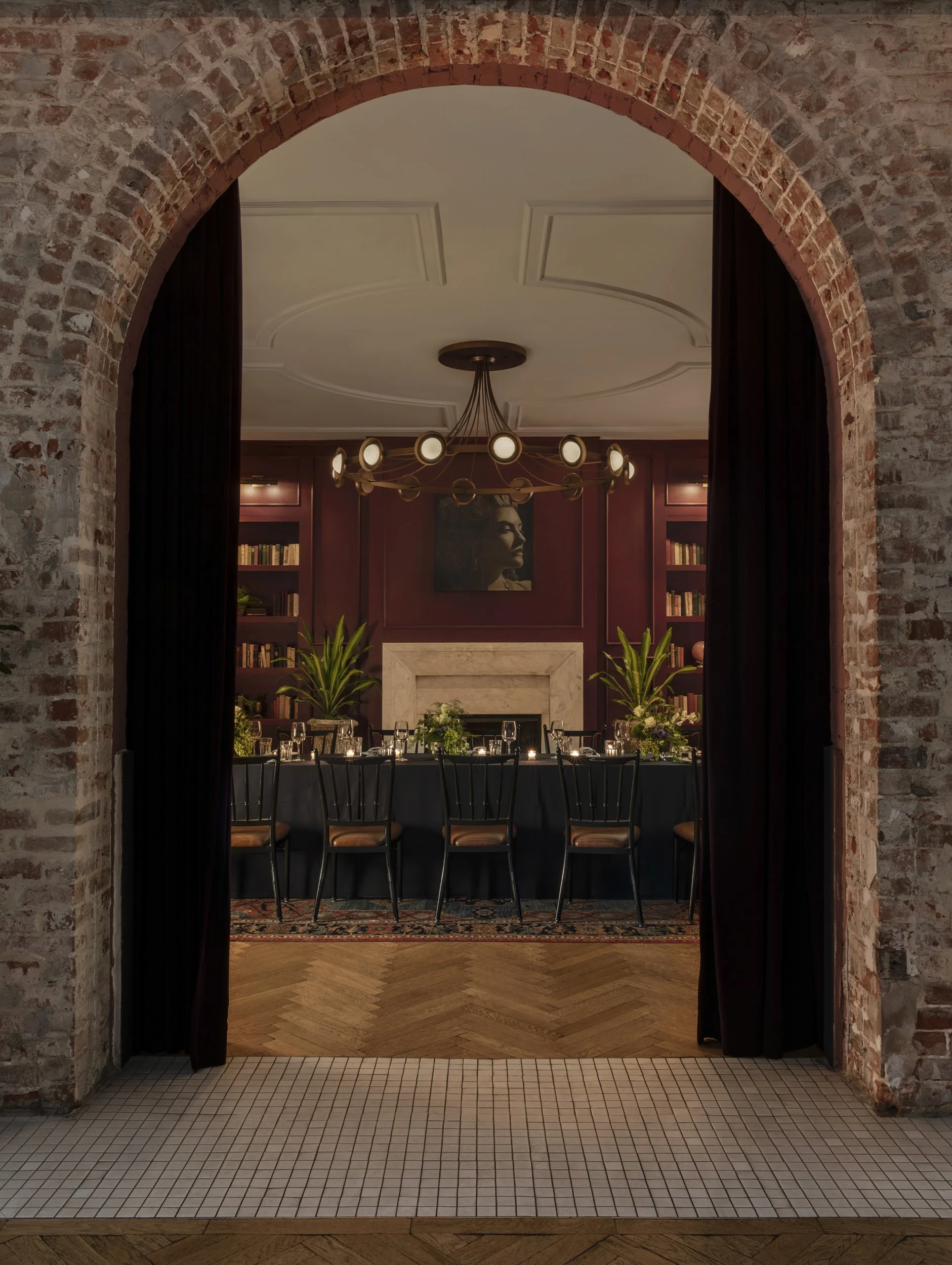 Brick archway looking into the library with chevron wood floor at the Eliza Jane