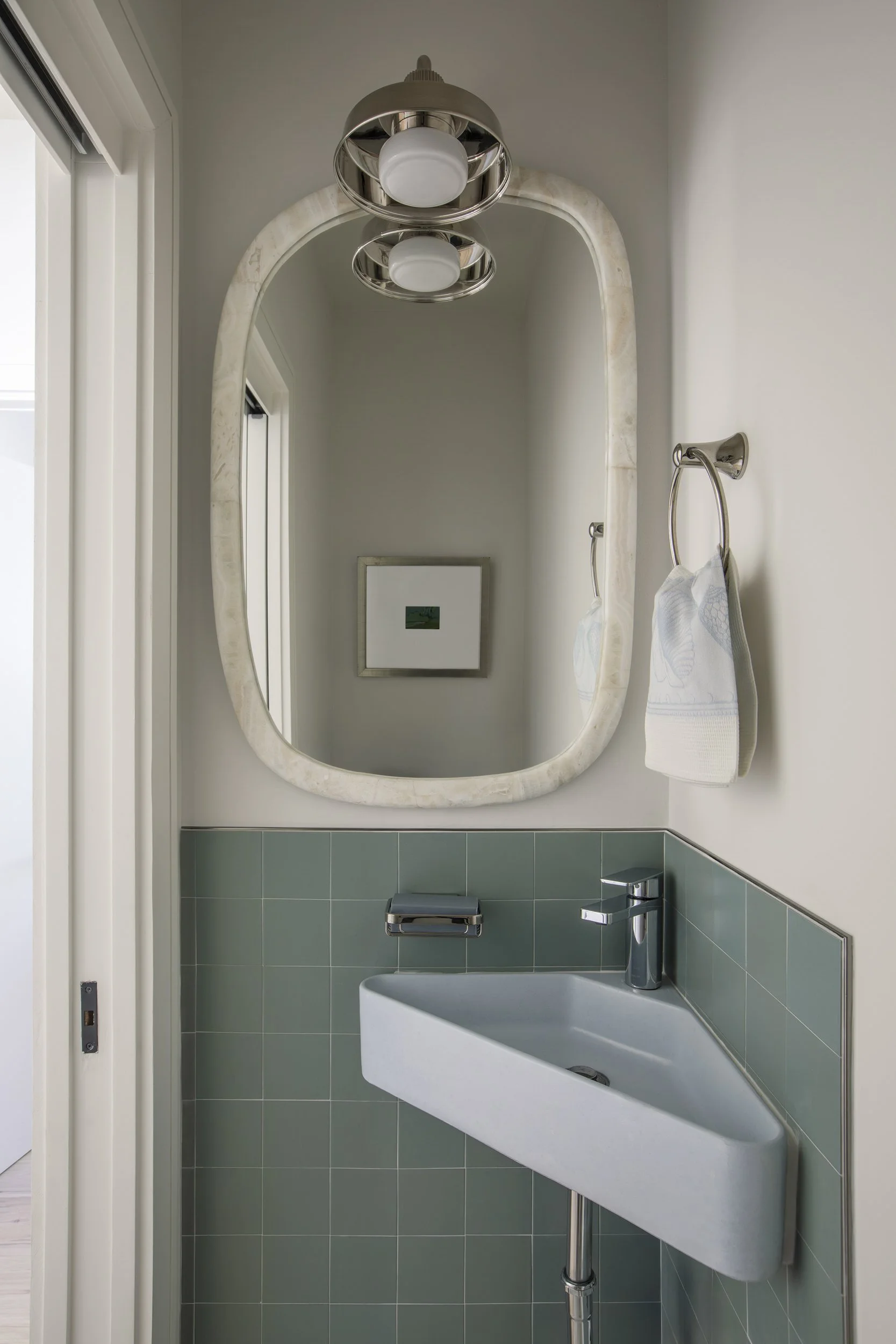 Powder room with oval mirror, green tile and wall-mounted sink at the Seaside