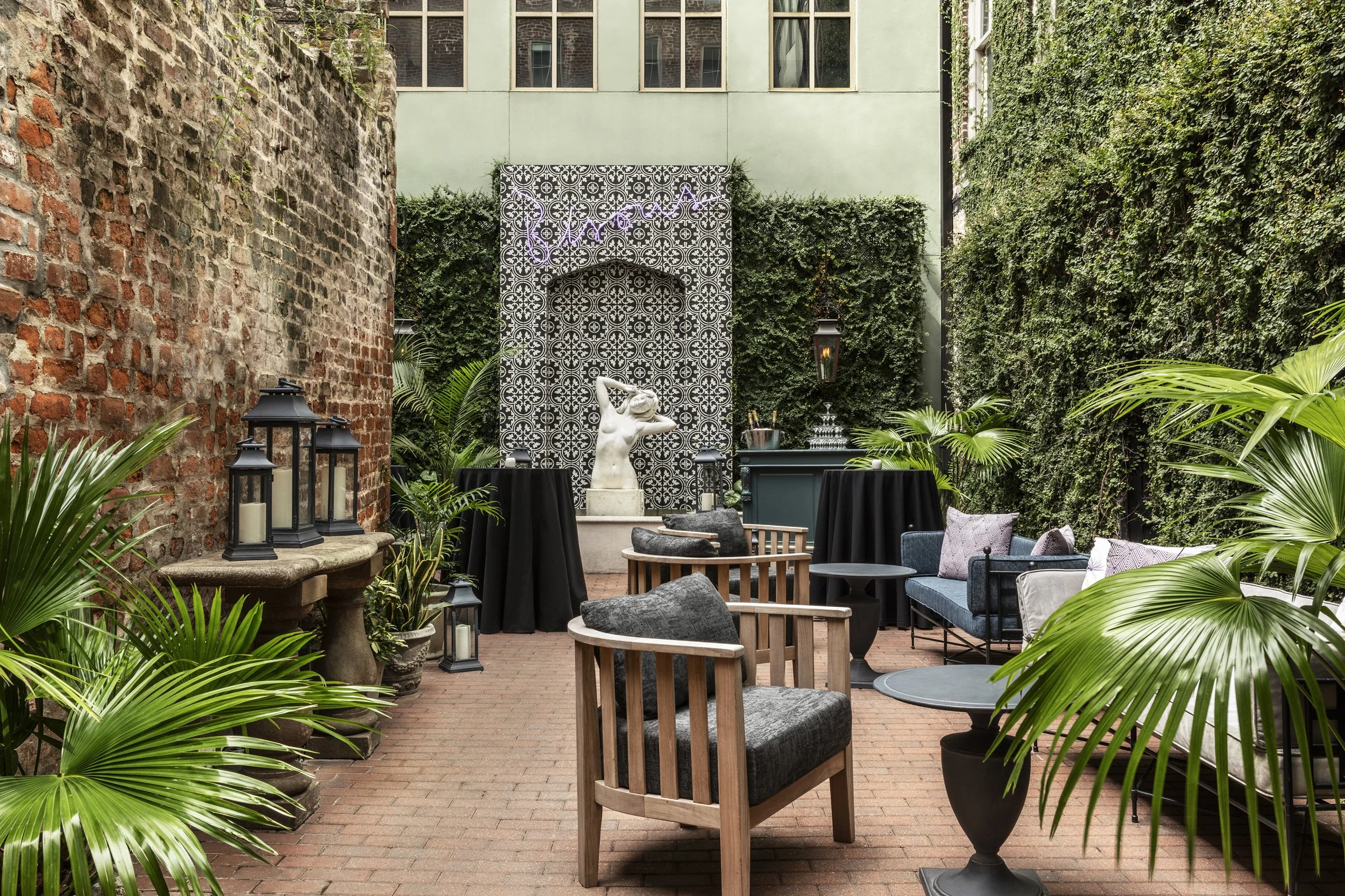 Courtyard with ivy-covered wall, palms and iron seating at the Eliza Jane