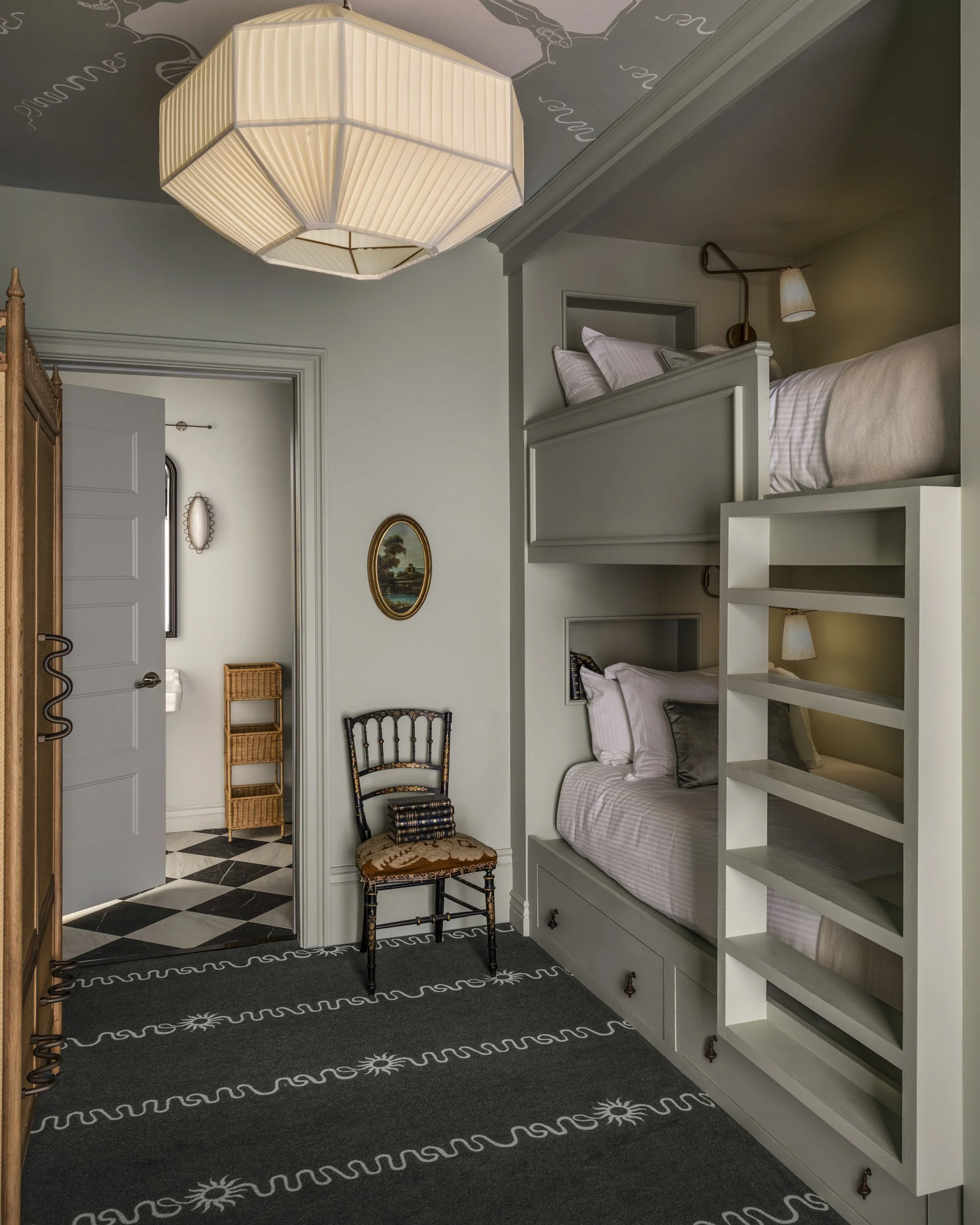 Bunk room with built-in beds, pleated pendant and checkerboard hallway beyond at the Perle