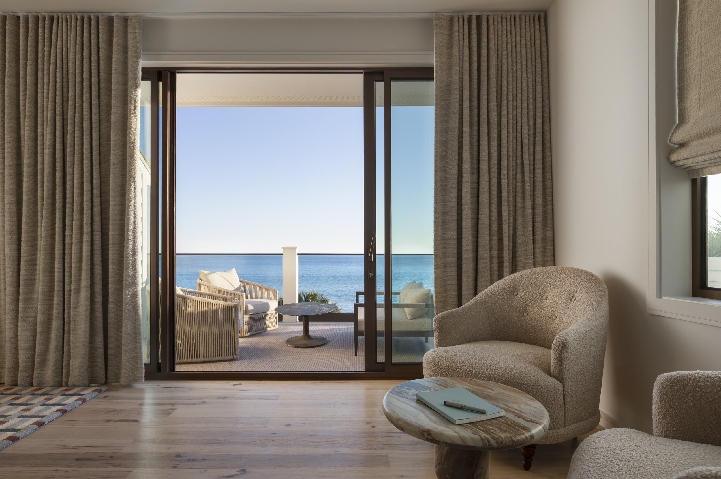 Coastal suite opening to an ocean terrace through sliding glass doors at the Seaside