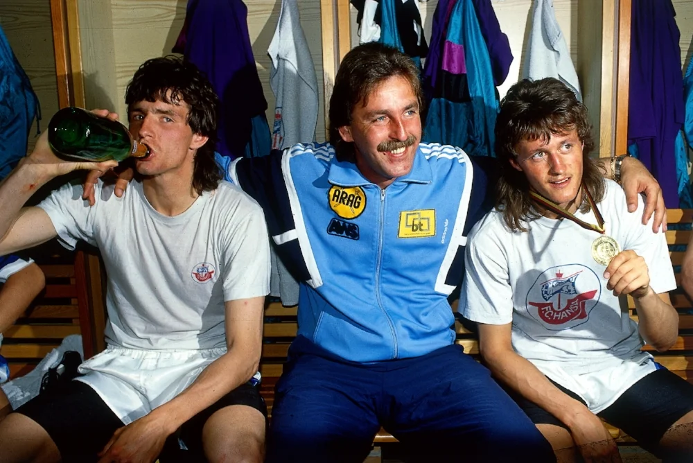Sagde du tysk fodboldhår? Hansa Rostocks træner Uwe Reinders sidder omgivet af Jens Wahl og Henri Fuchs efter pokaltriumfen i 1990/1991-sæsonen. Foto: Getty Images
