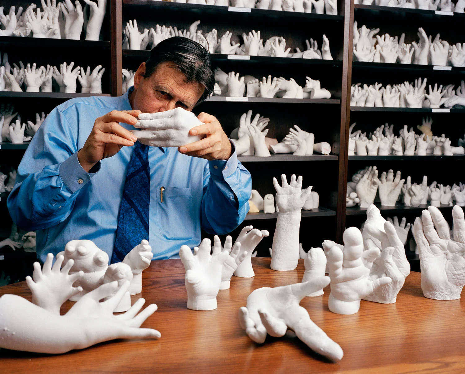 Surgeon with molds of hands he has repaired, Brookline, MA, 2002