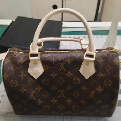 Louis Vuitton handbag with monogram pattern on a cluttered desk.