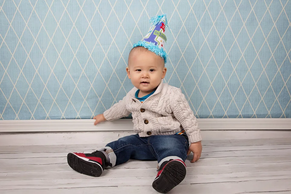 Adorable-little-boy-wearing-birthday-hat-at-milestone-session-at-Calgary-photography-studio