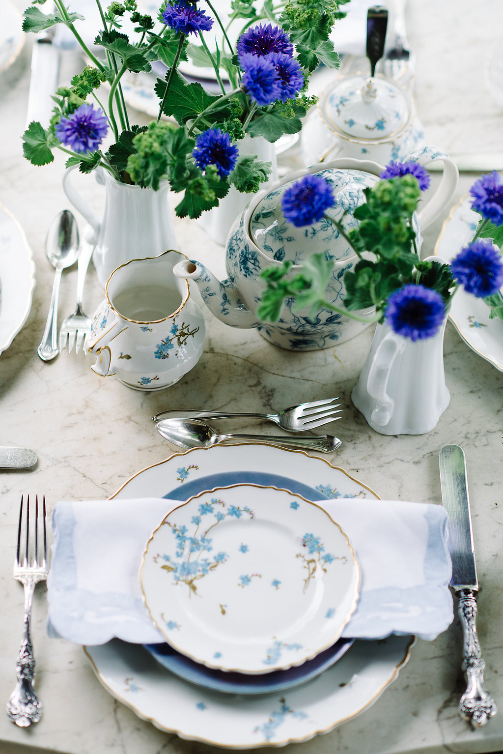 The marble table on the front porch was in the inspiration for this table. Cindy’s mother’s china with a forget-me-not pattern was perfect paired with the bachelor buttons and ladies mantle. Photo: Norman Photo and Paper