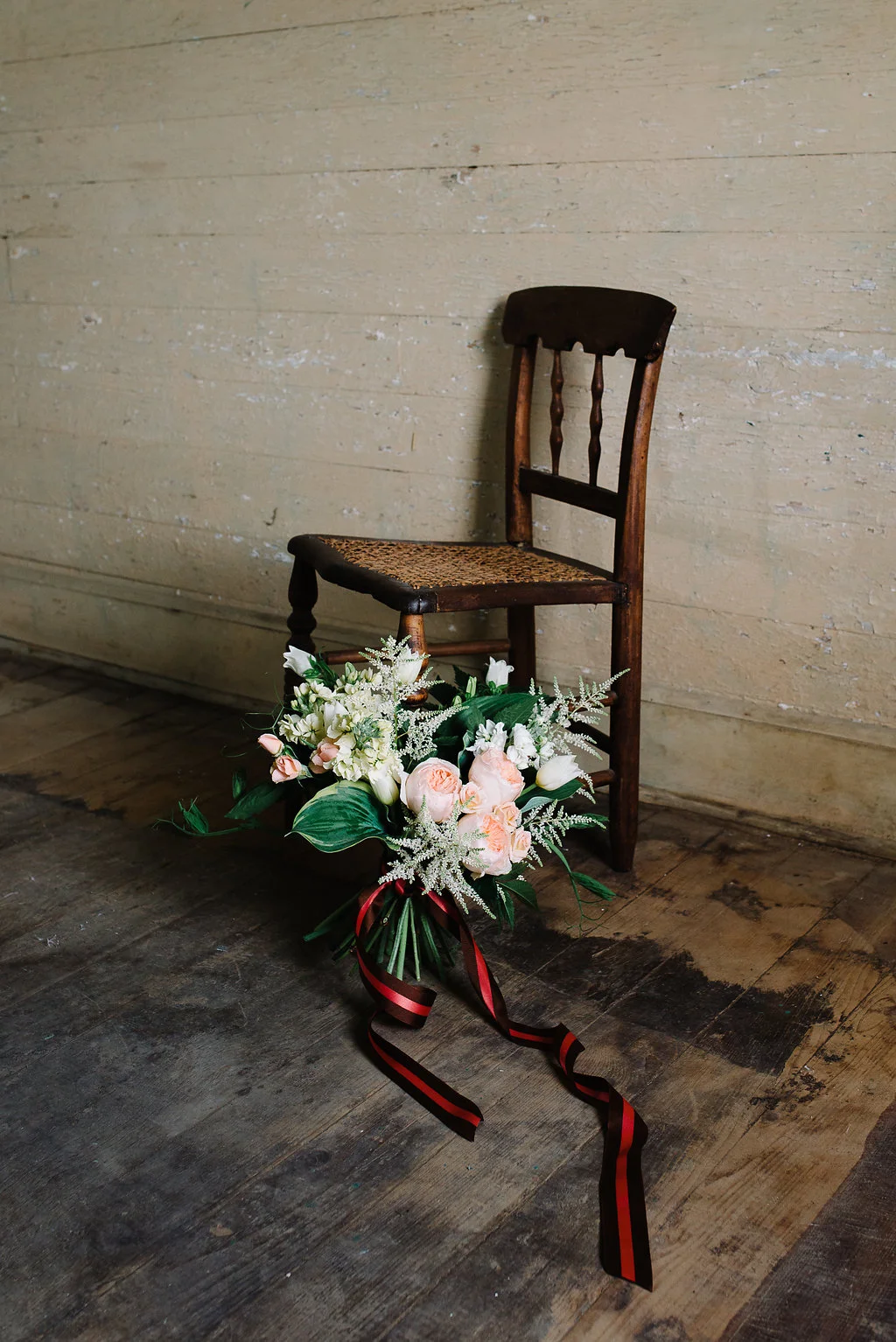 Bouquet with hosta, astilbe, garden roses, stock, tulip, campanula and pea shoots resting against a 19th century cane chair.  Photo by Norman Photo and Paper.