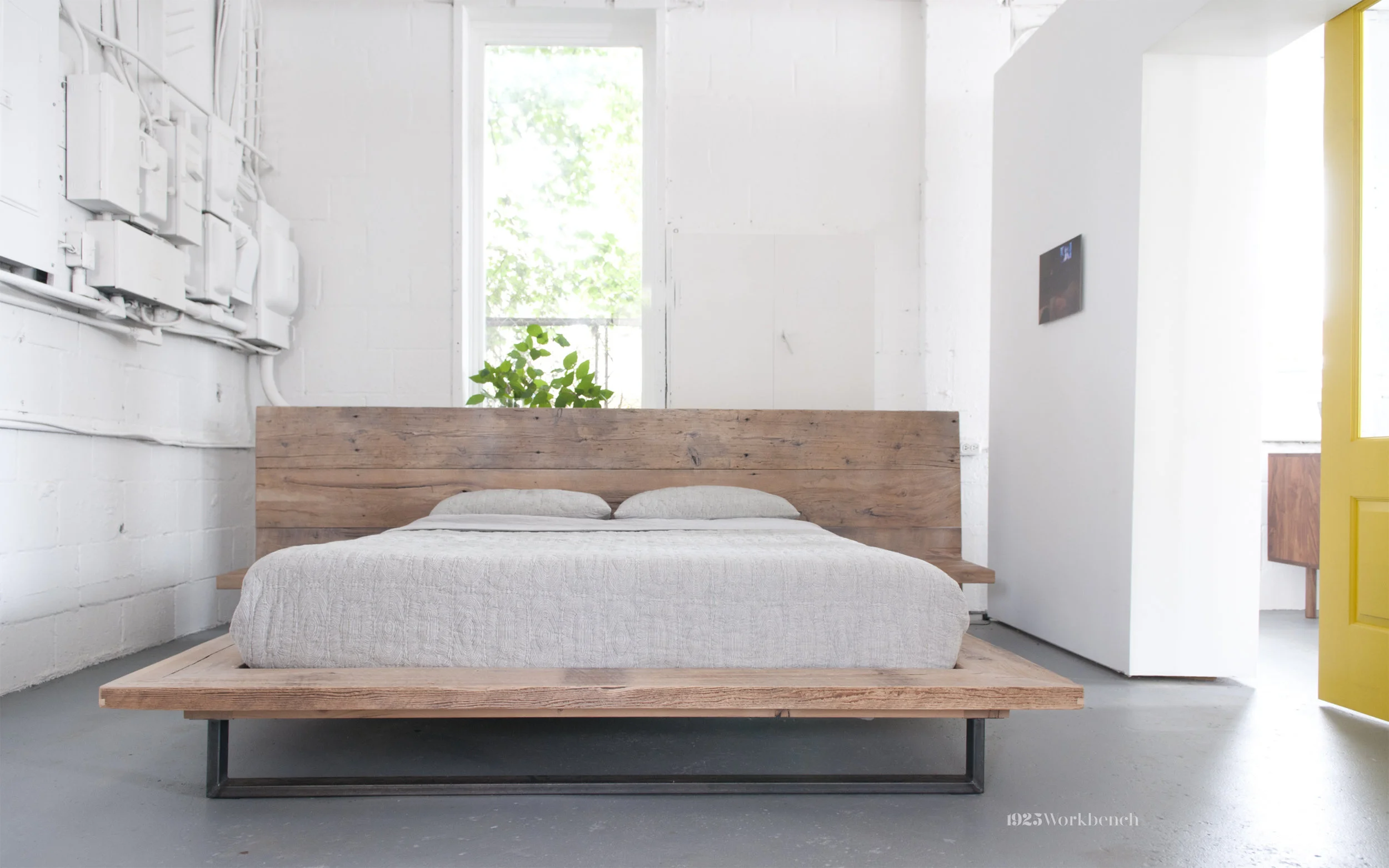 Here is our platform bed inside made of reclaimed wood. The left wall are electrical panels from the machine shop before us. we decided to leave them on the wall and paint them all white as an installation and to reclaim a piece of the building's history.