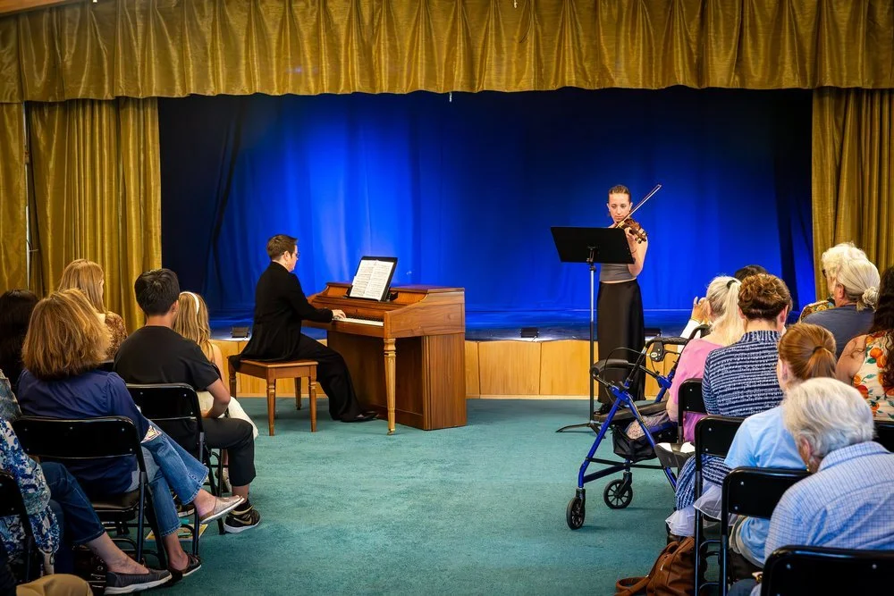  Co-founder/President Lacey McNamara performs with a young violinist at a fundraiser concert.  Photo by RyLo Media Design 