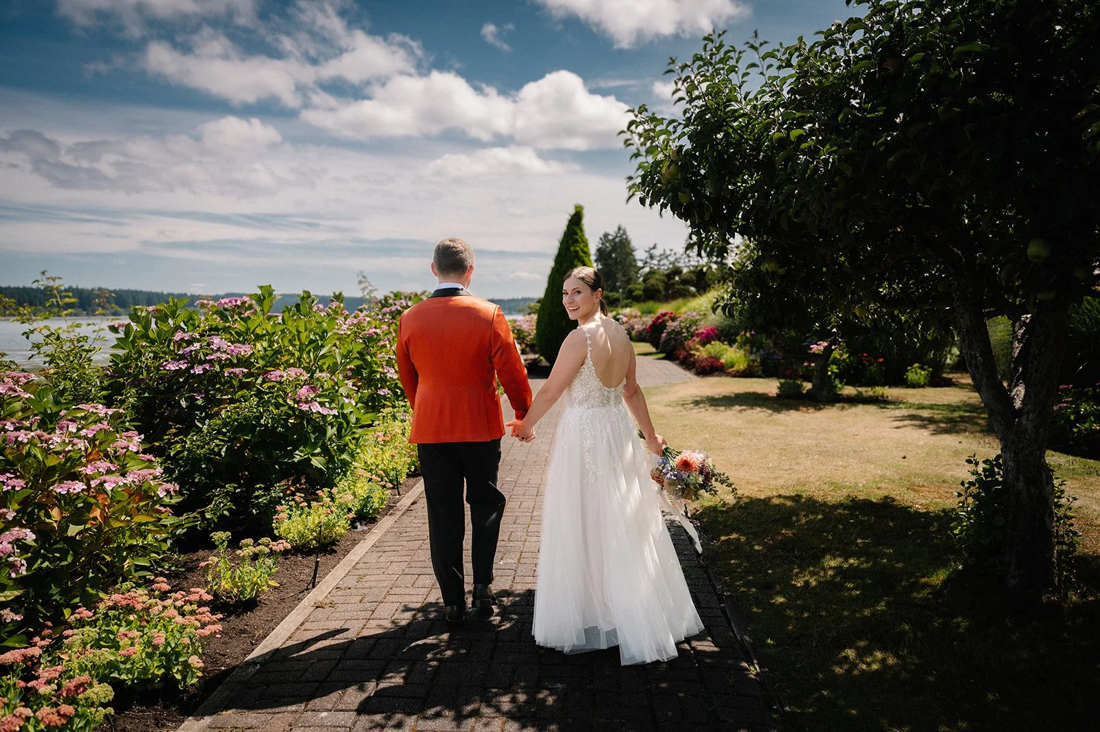 wedding couple walking hand in hand surrounded by flowers during their garden wedding day in seattle