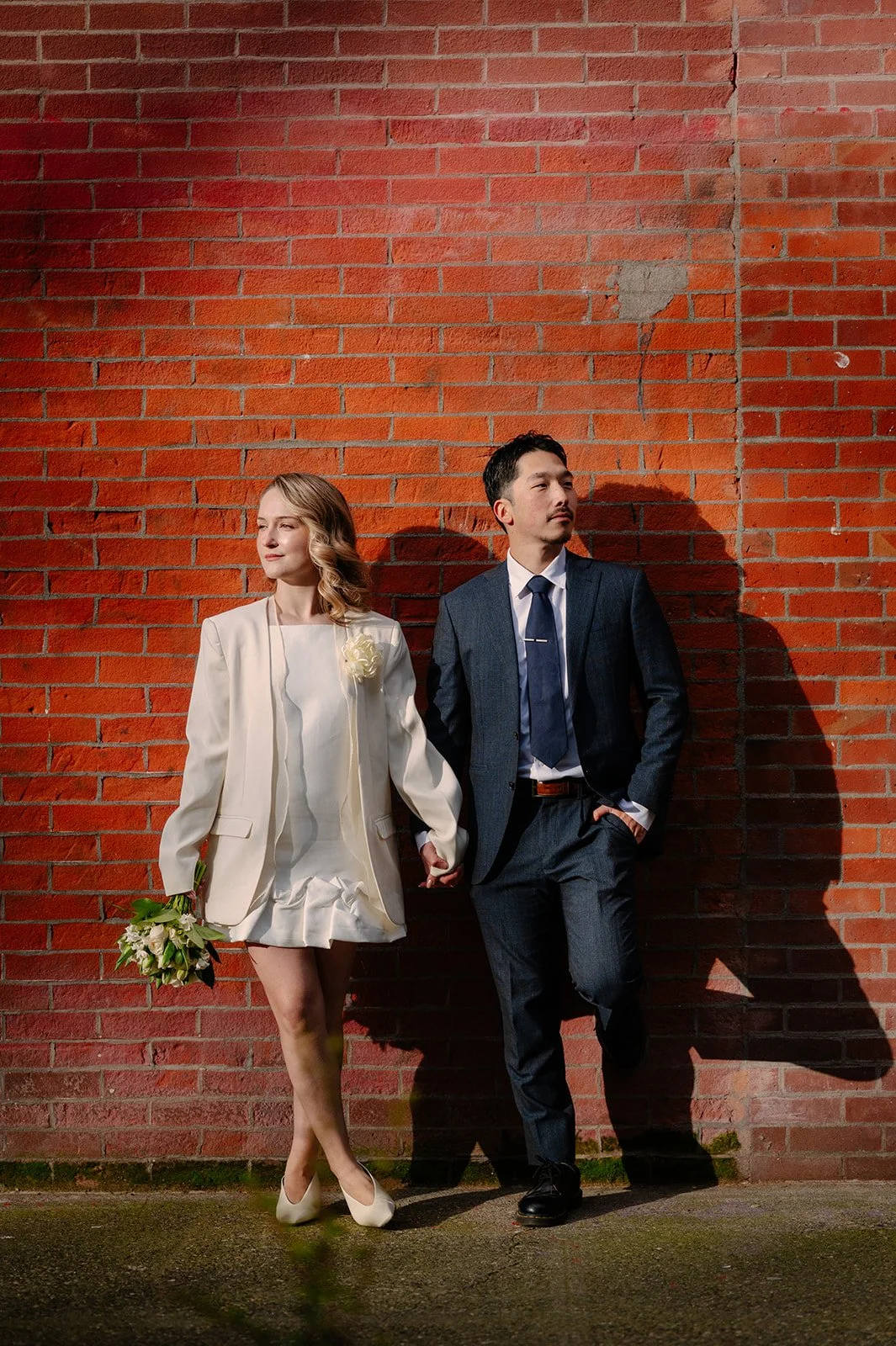 elopement couple holding hands in front of a red brick wall during their seattle elopement