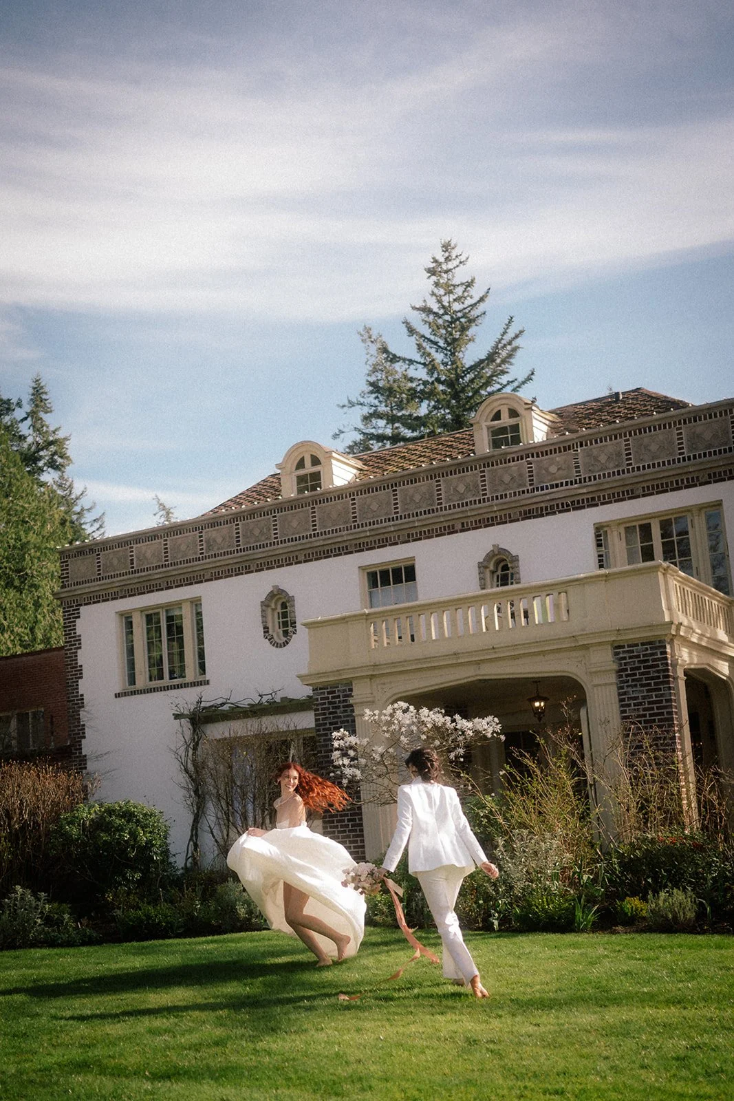 queer wedding couple running around the lush grounds during their lairmont manor wedding