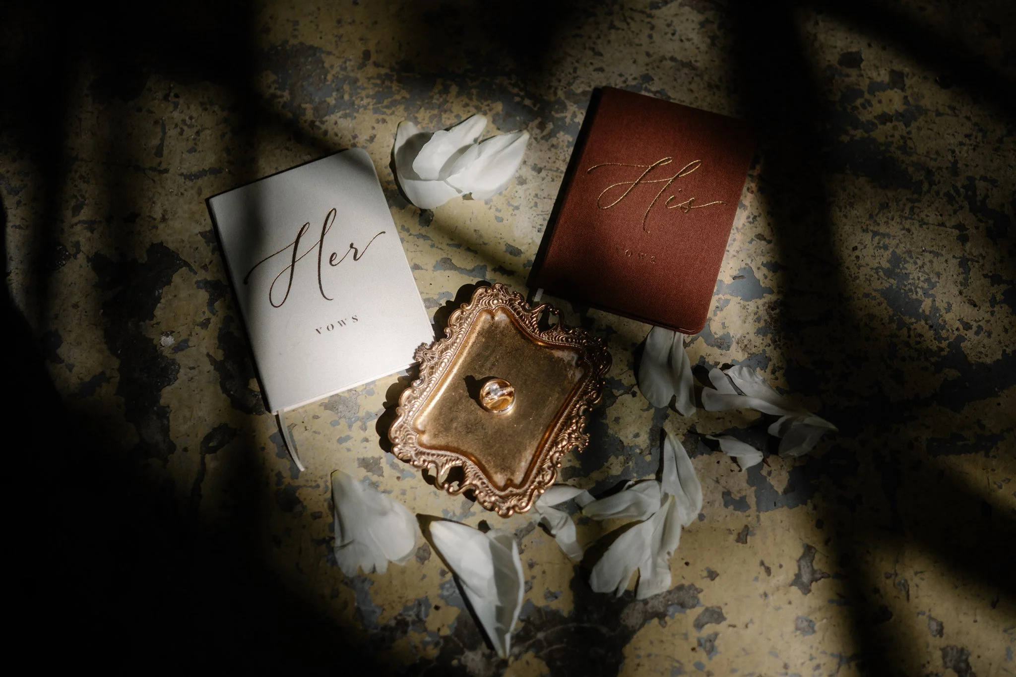 Moody wedding flat lay photography with petals and wedding stationery