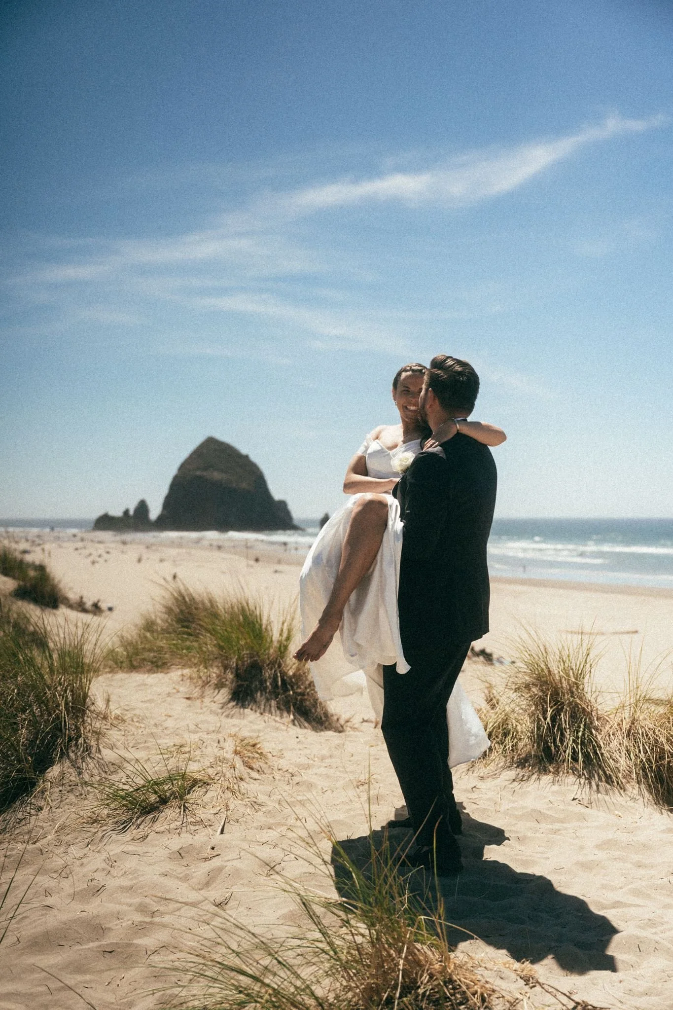 playful wedding couple at the beach during their cannon beach wedding on the oregon coast