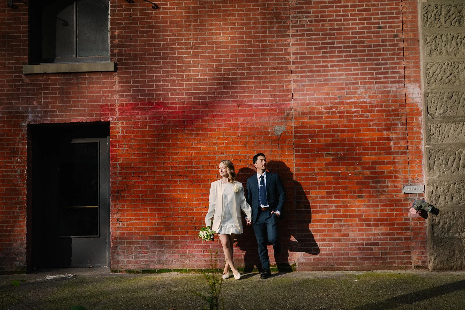 elopement couple hugging in front of a red brick wall during their seattle elopement