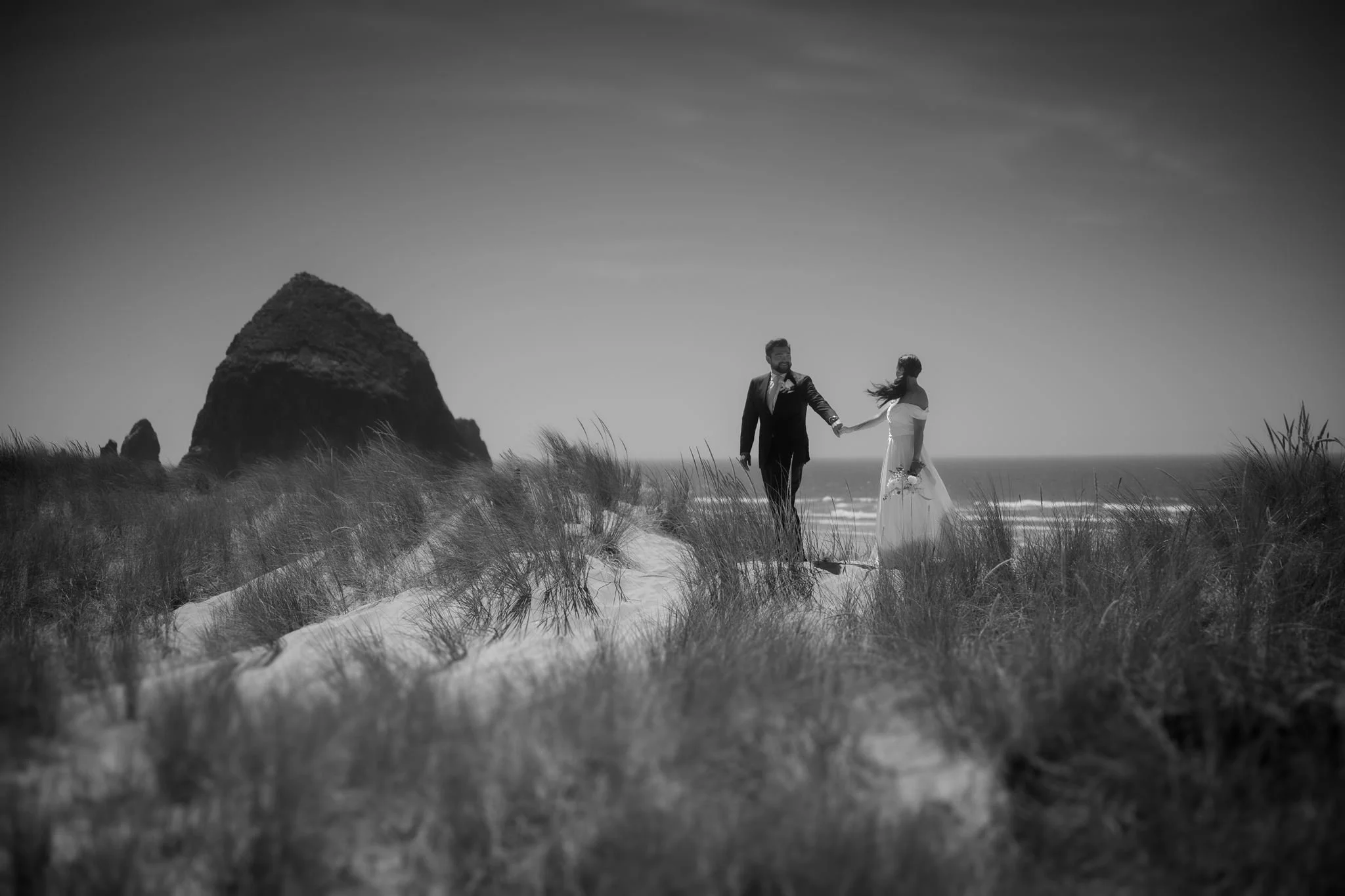 black and white photo of bride and groom at the beach during their cannon beach wedding on the oregon coast