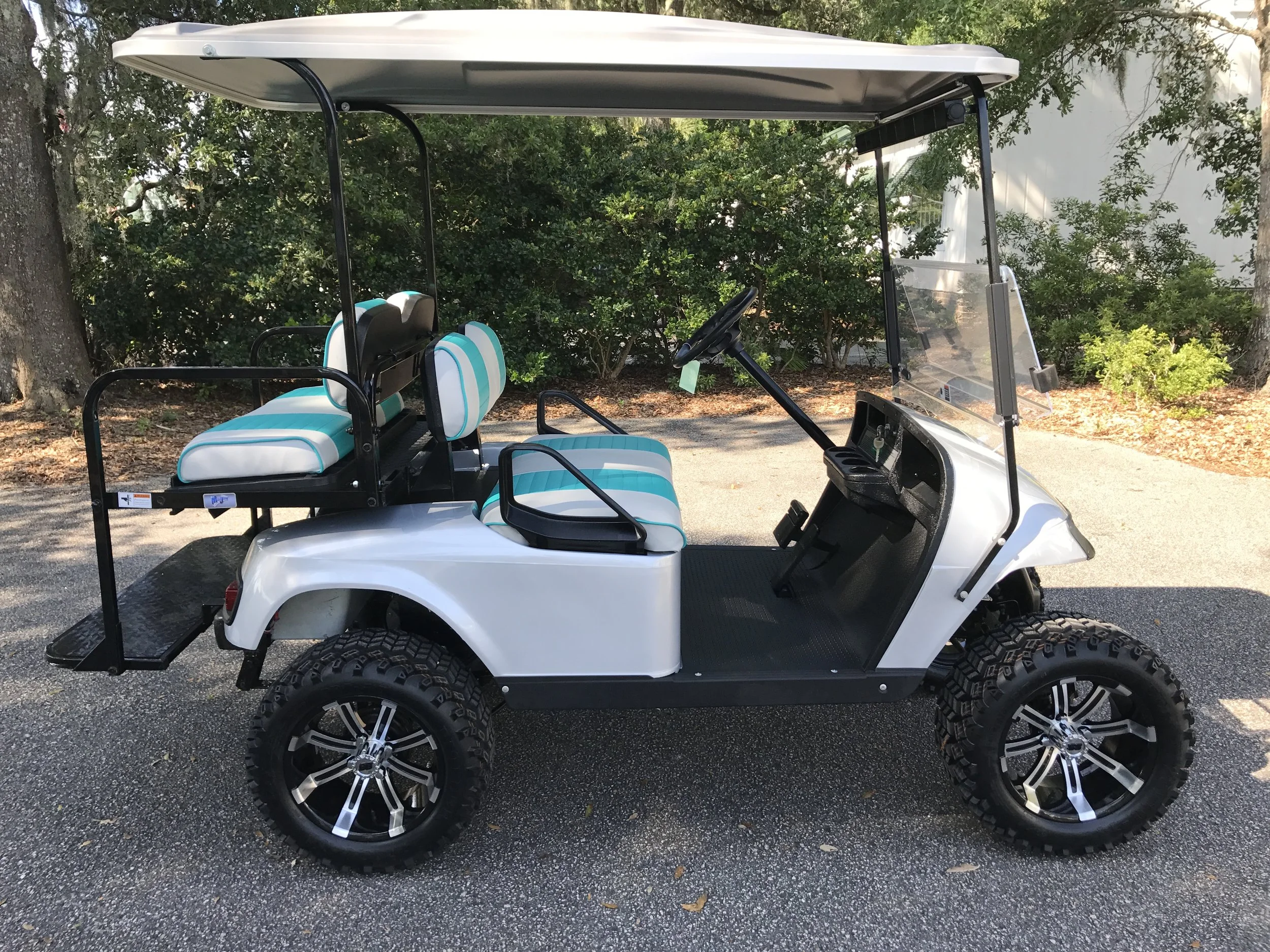 Silver EZGO Lifted Cart Silver/emerald seats, white extended top, new (2017) batteries, high speed code, LED lights, mirror, flip windshield, Backlash (23x10x14) tires, and state of charge meter