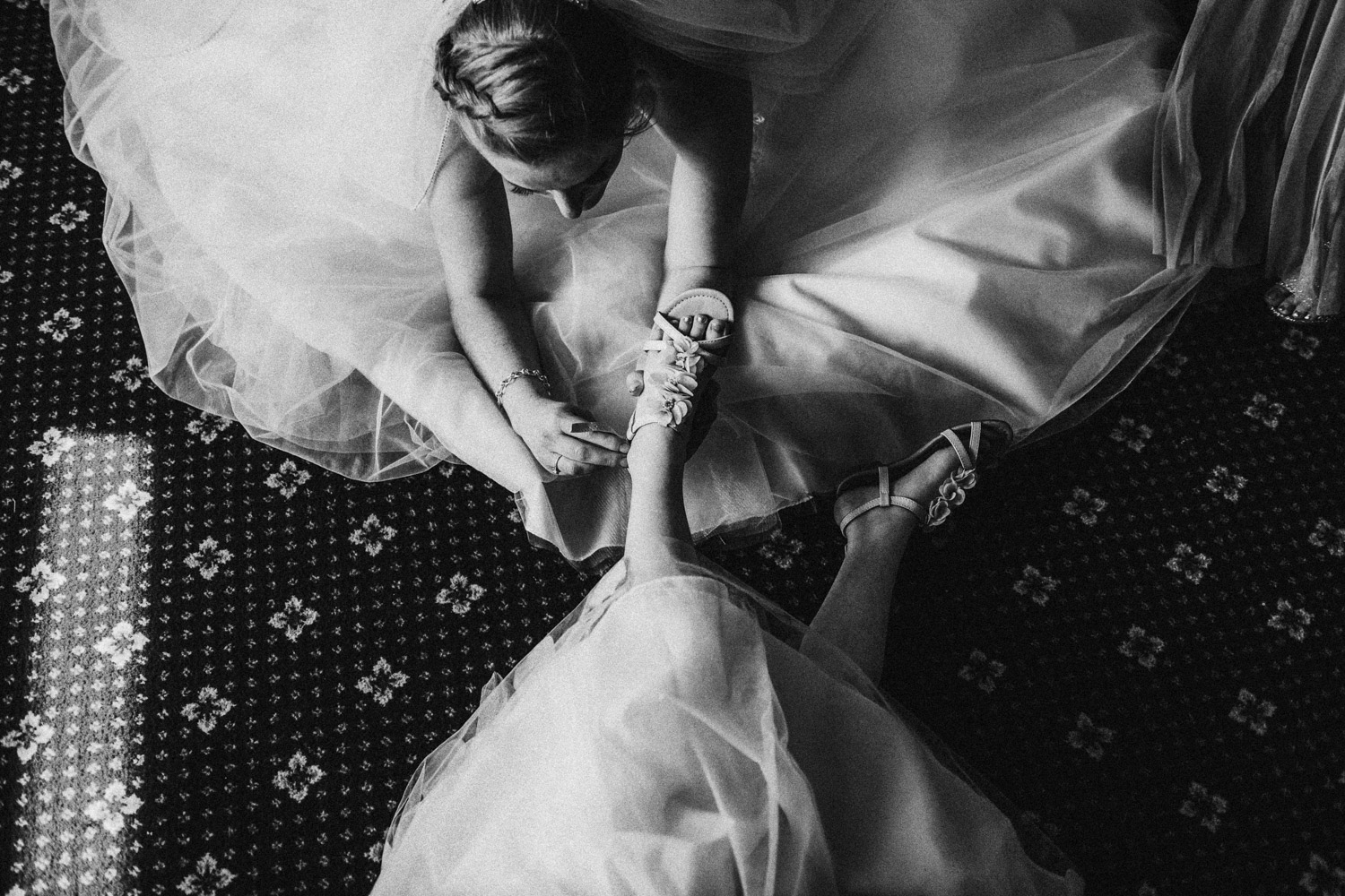 bride helping daughter with shoe