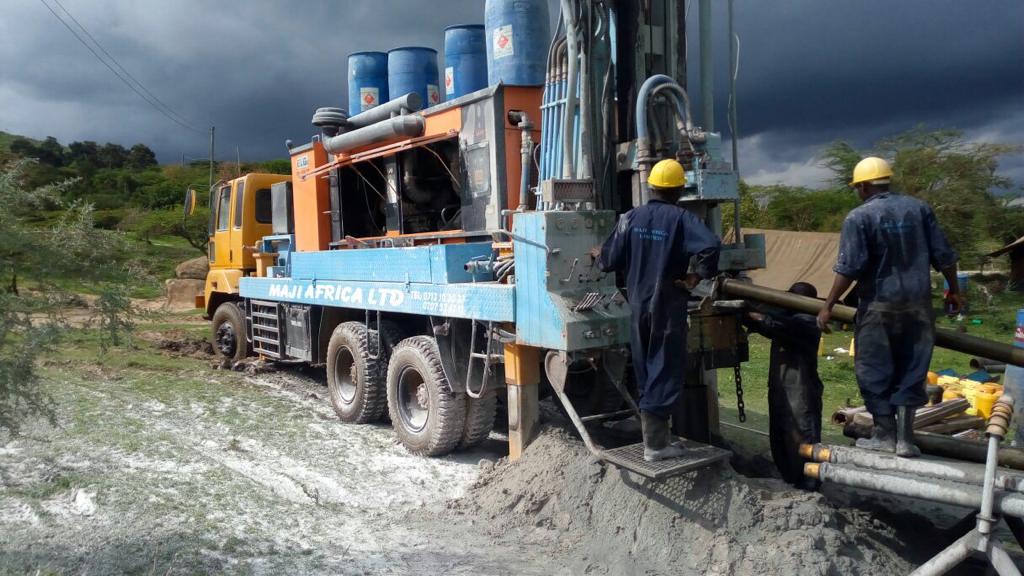 Workers from Maji Africa lowering water pipes into the well after they completed the drilling process.