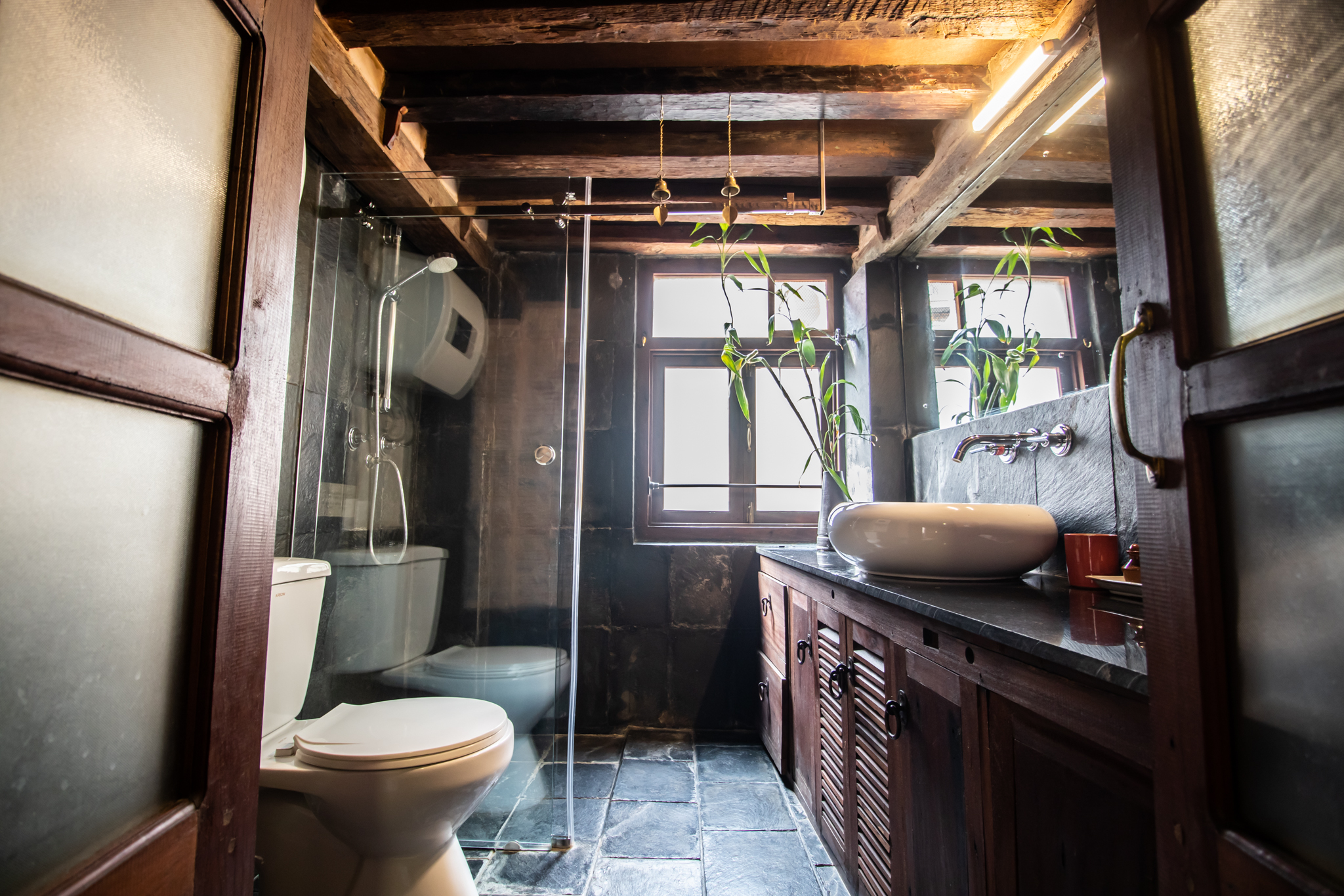 Modern and spacious wood and stone bathroom with hot water shower.