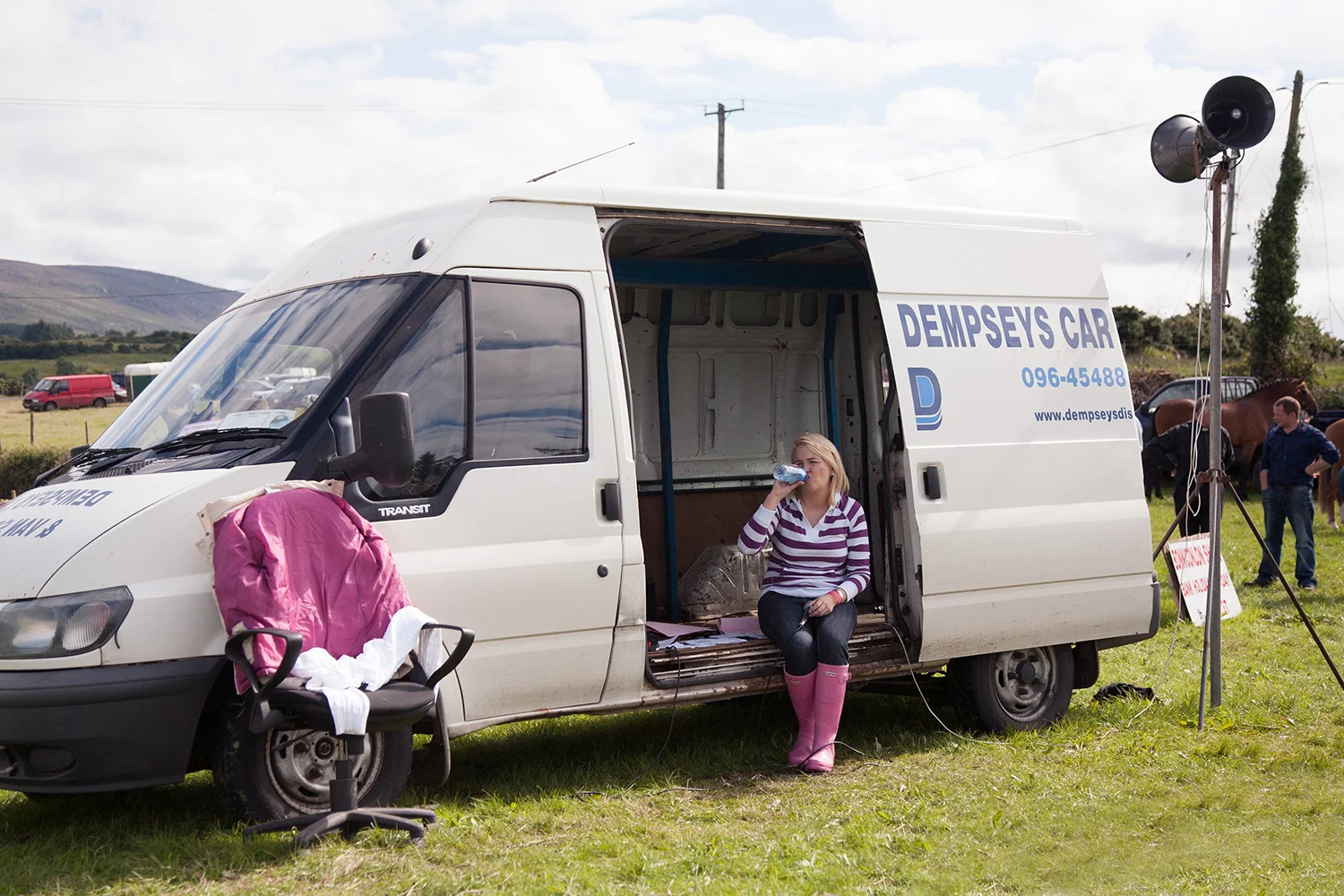 A documentary photograph of a woman drinking water in her new van at an agricultural show in the west of ireland