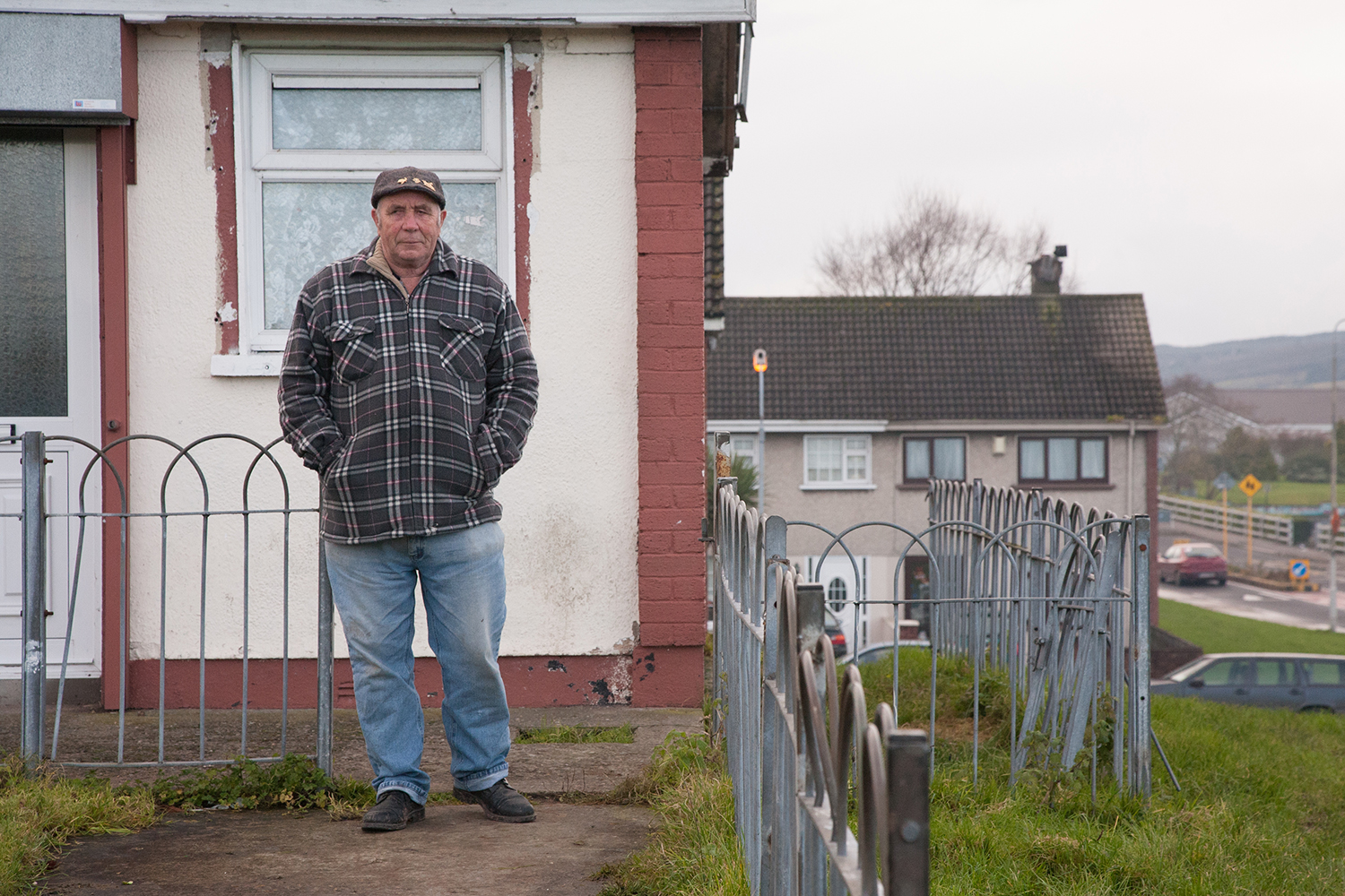 A documentary photograph of a man watching the monks of moires from his doorstep in Moyross, Limerick, Ireland