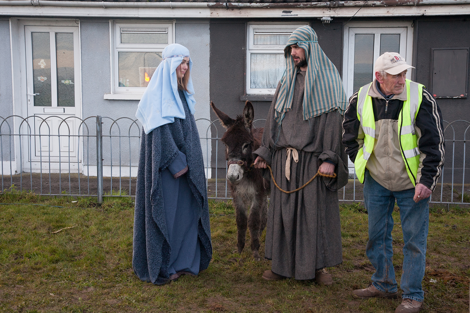 A documentary photograph of a man standing by two actors before they perform a live nativity with the monk of moires in Limerick, Ireland