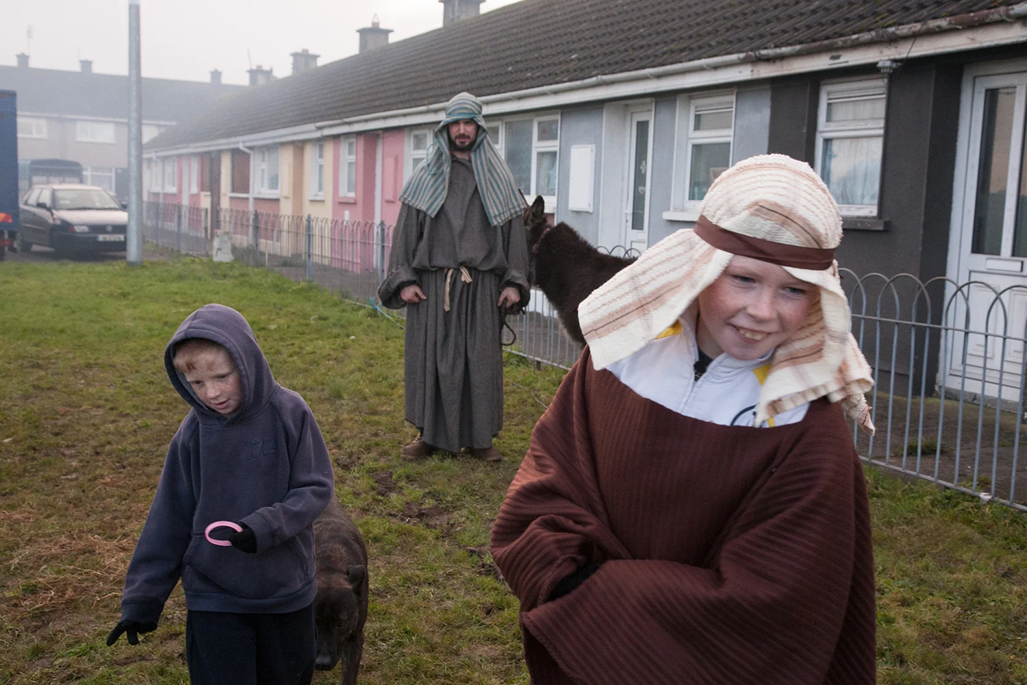 A documentary photograph of two boys walking away from a man and a donkey before they perform a live nativity scene with the Monks of Moyross in Limerick City