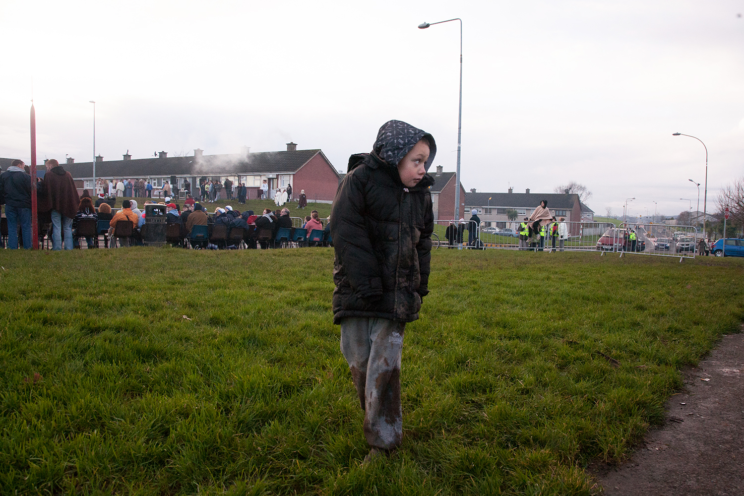 A documentary photograph of a boy walking away from the crowd as the monks perform a live nativity scene in Moyross, Limerick, Ireland