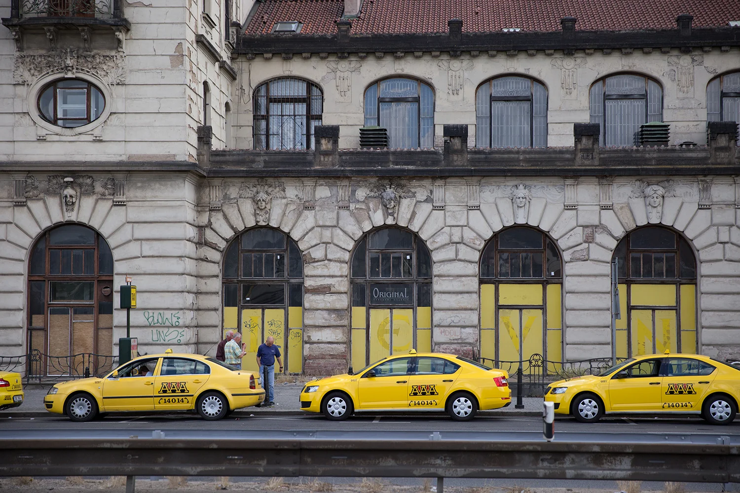A documentary photograph of yellow taxi cabs waiting outside the train station in Prague, Czech Republic