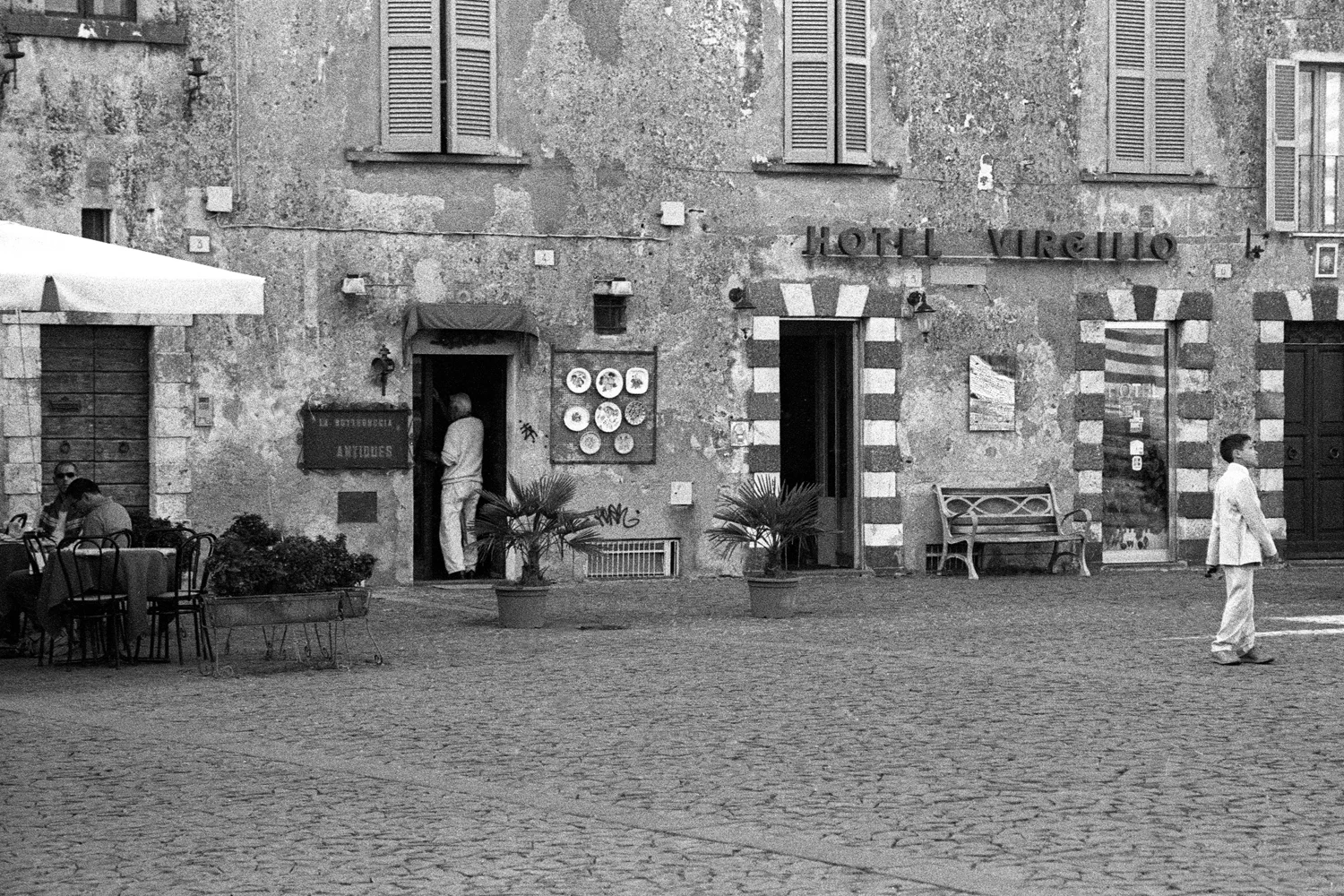 A documentary photograph of a boy walking through a square in Italy