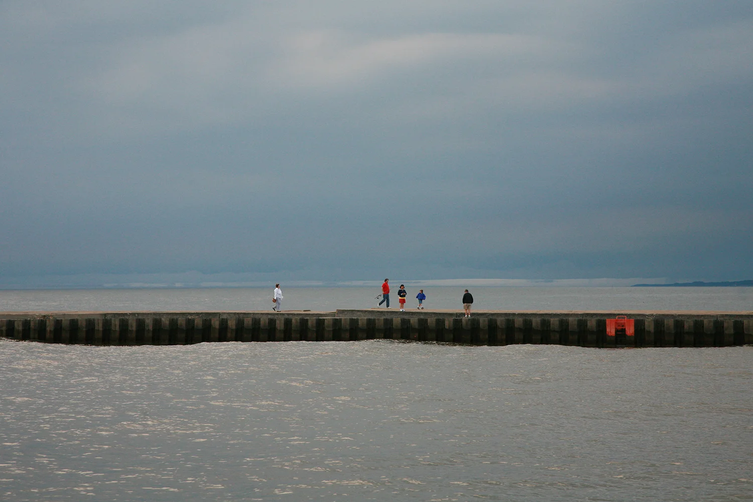 A documentary photograph of people walking along the pier in lake michigan