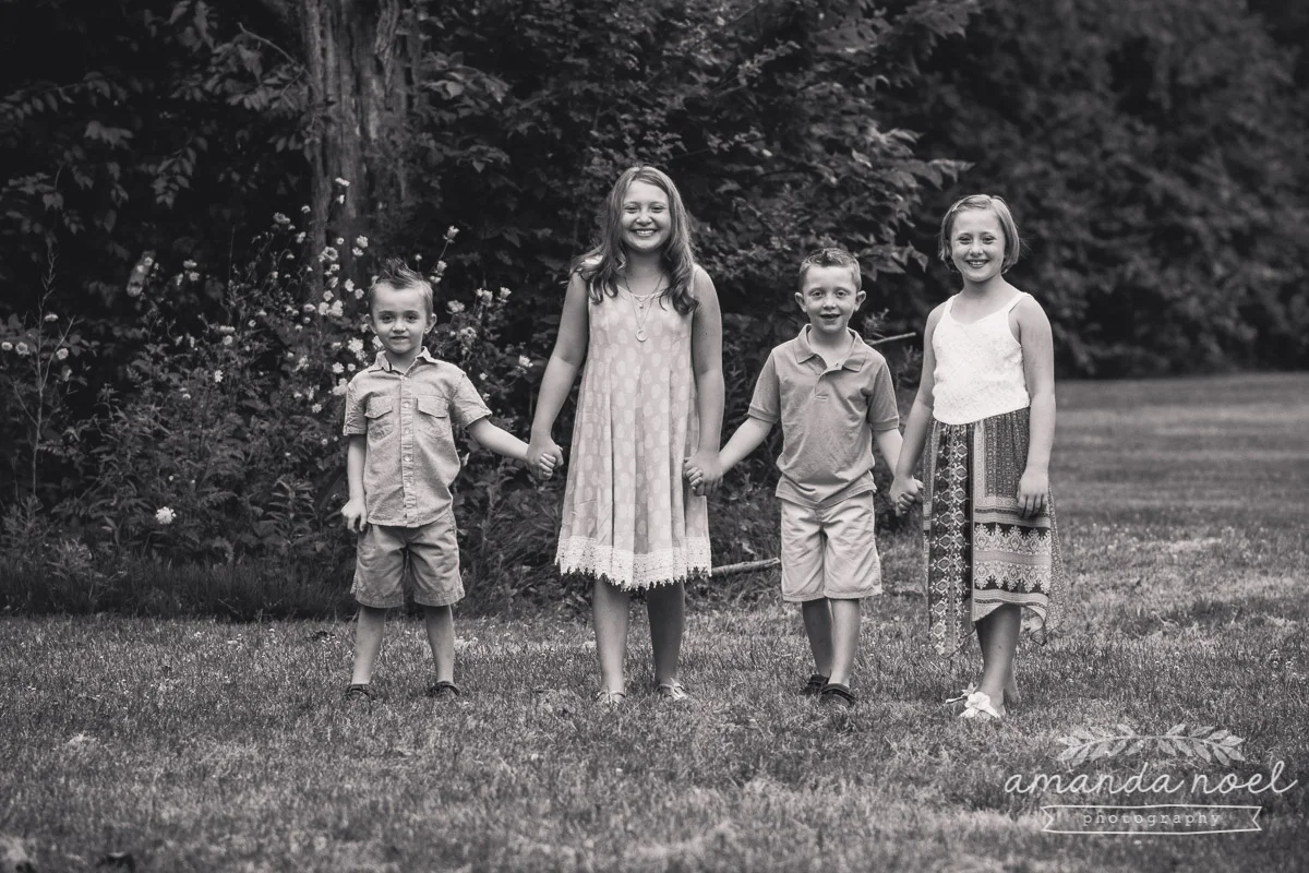 4-siblings-holding-hands-in-field-black-and-white