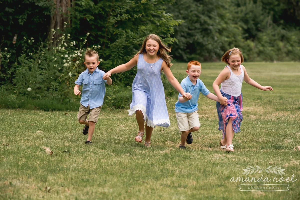 4-siblings-in-blue-holding-hands-running-in-Springfield-Ohio-field