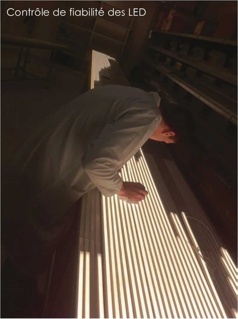 Un homme en blouse de laboratoire inspecte un panneau lumineux à LED, soulignant la fiabilité de l'éclairage.