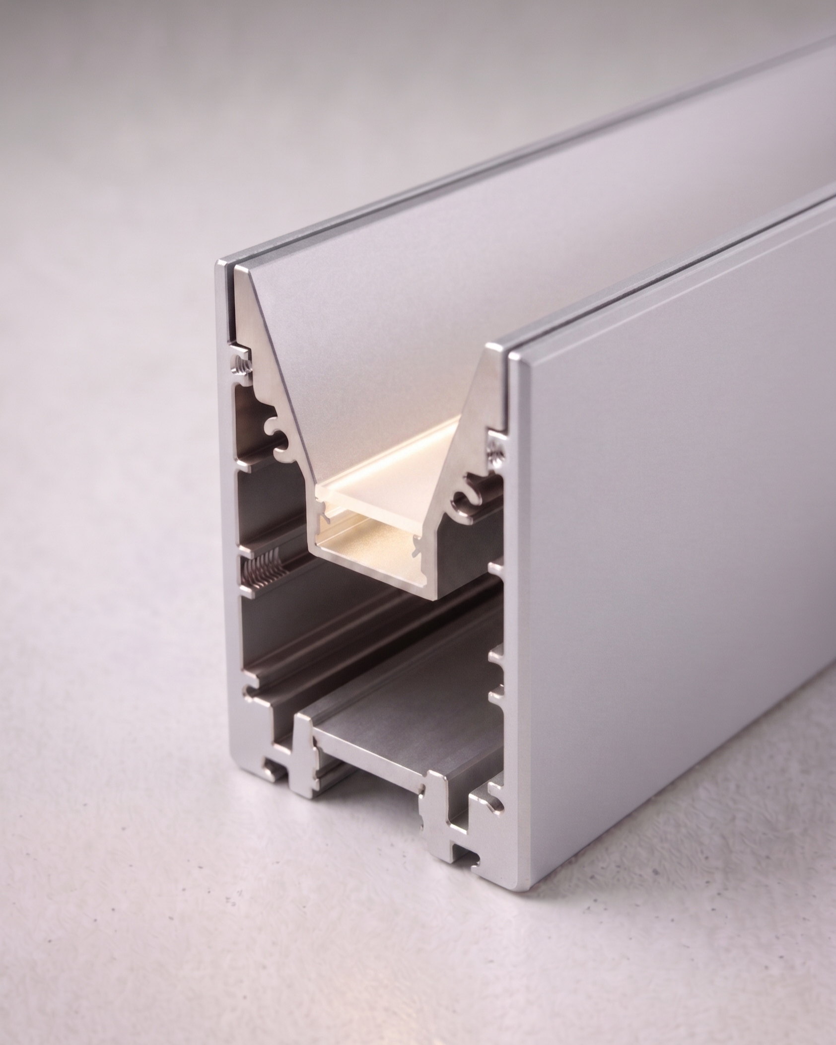 Vue partielle d'un ordinateur portable en aluminium avec un écran fermé, placé sur une surface en béton clair.