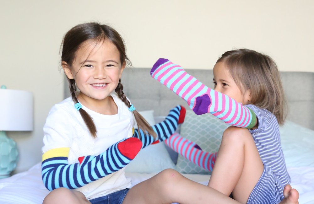 Kids wearing colorful We Help Two socks