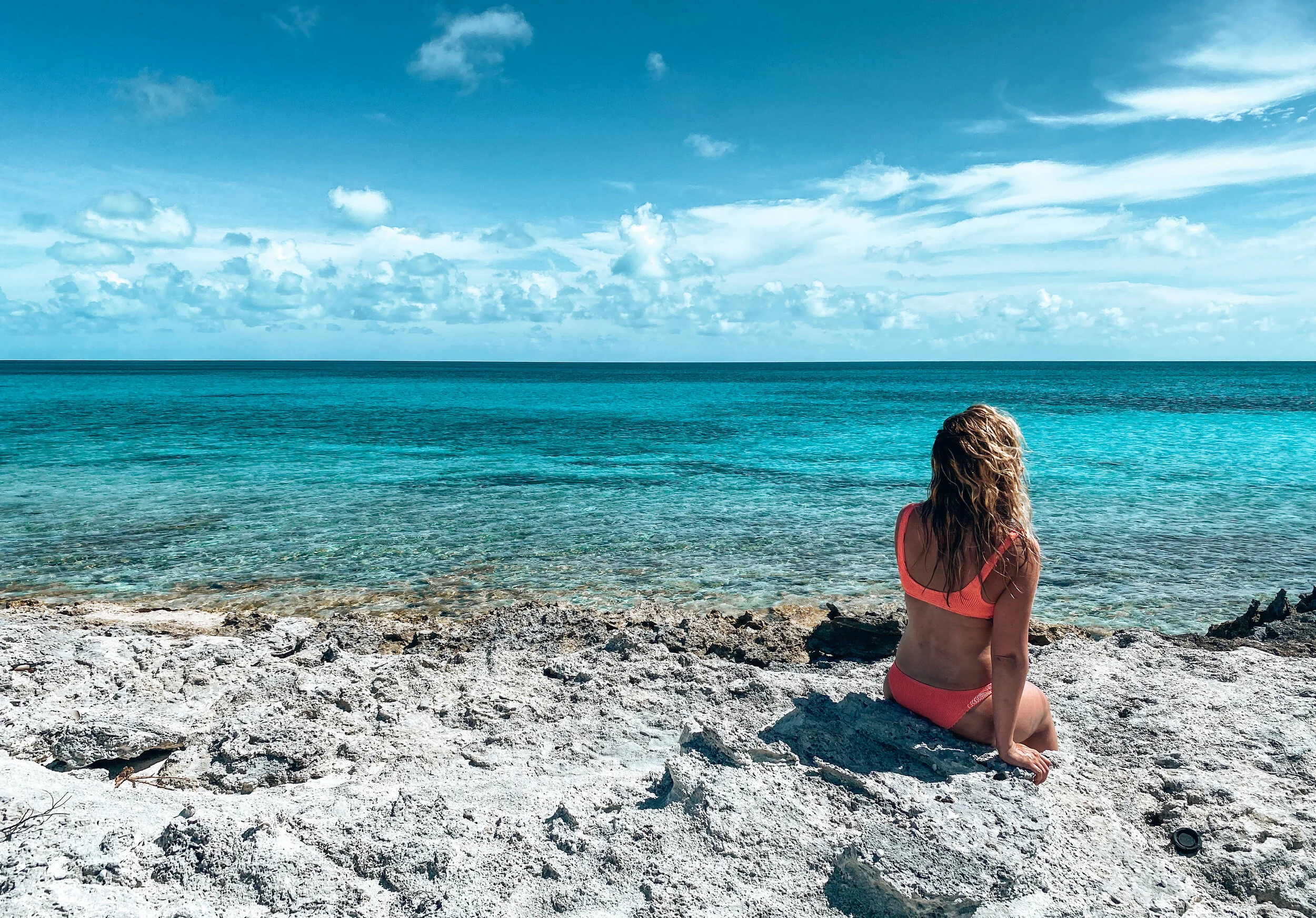  Blonde beach bade sitting by the beach and looking at the shoreline in the Bahamas. 