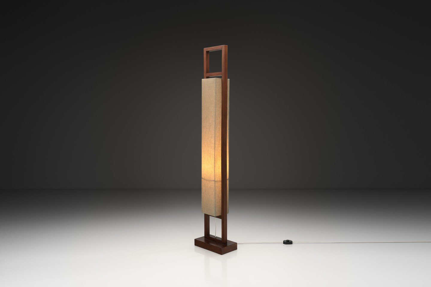 This floor lamp embodies the essence of modernist design where simplicity, quality materials, and precision craftsmanship converge. The solid wood frame and linear composition creates a strong vertical presence, rooted in the design principles that d