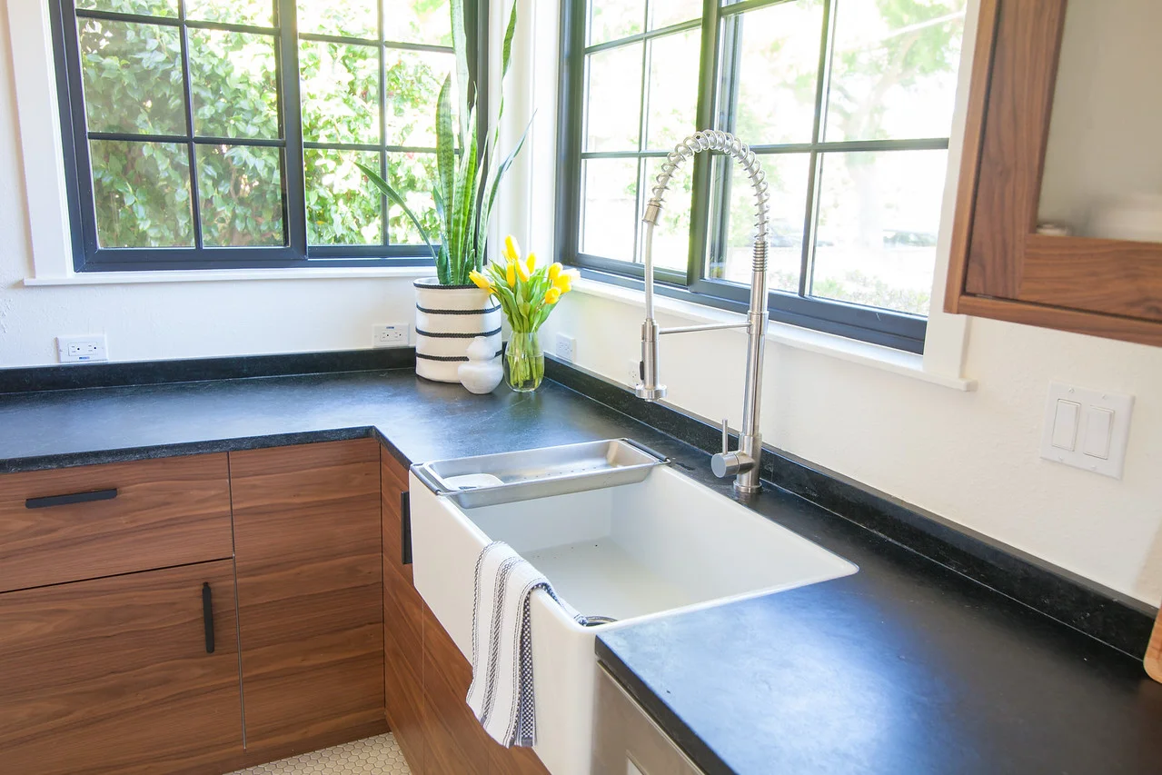After: The formerly corner-situated sink is re-positioned for easier access and replaced with a new Farmhouse Fireclay sink and flanked by new windows.