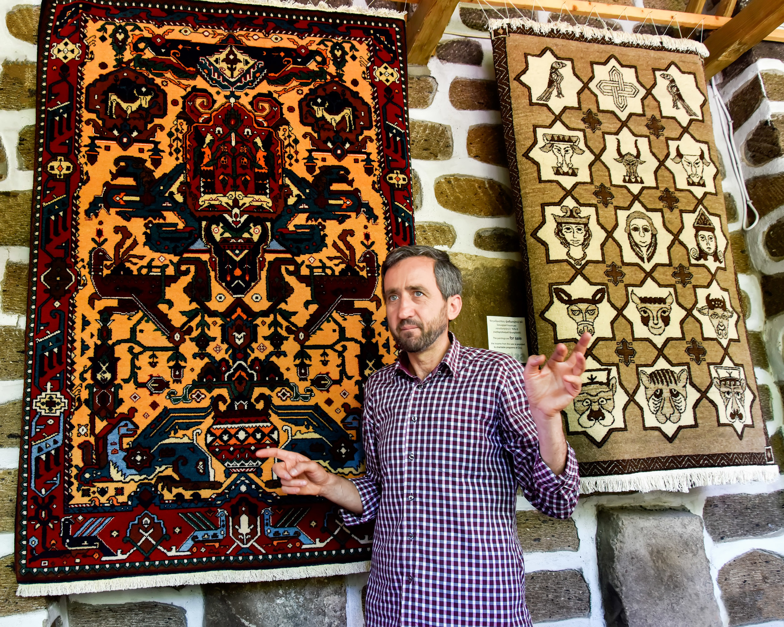 Grigor Machanents, founder of CAU. The rug on your left is a unique design of ancient pagan origin. On your right is a rug with important symbols of the Armenian Christian church. Both are important parts of the long, rich history of Armenia.