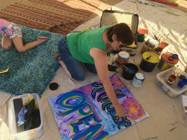Ann painting ArtHouse sign at Moonlight Market