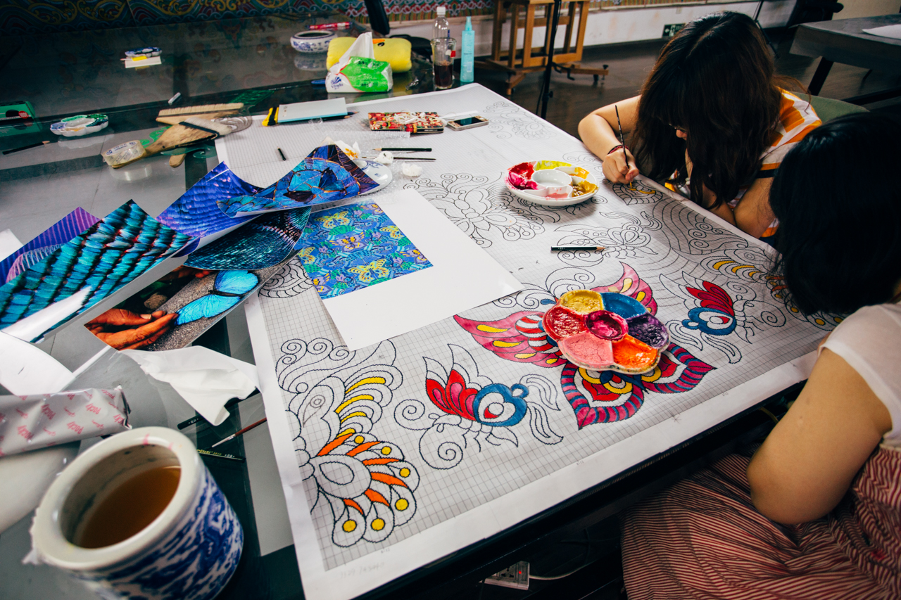 Brocade apprentices painting the patterned grid