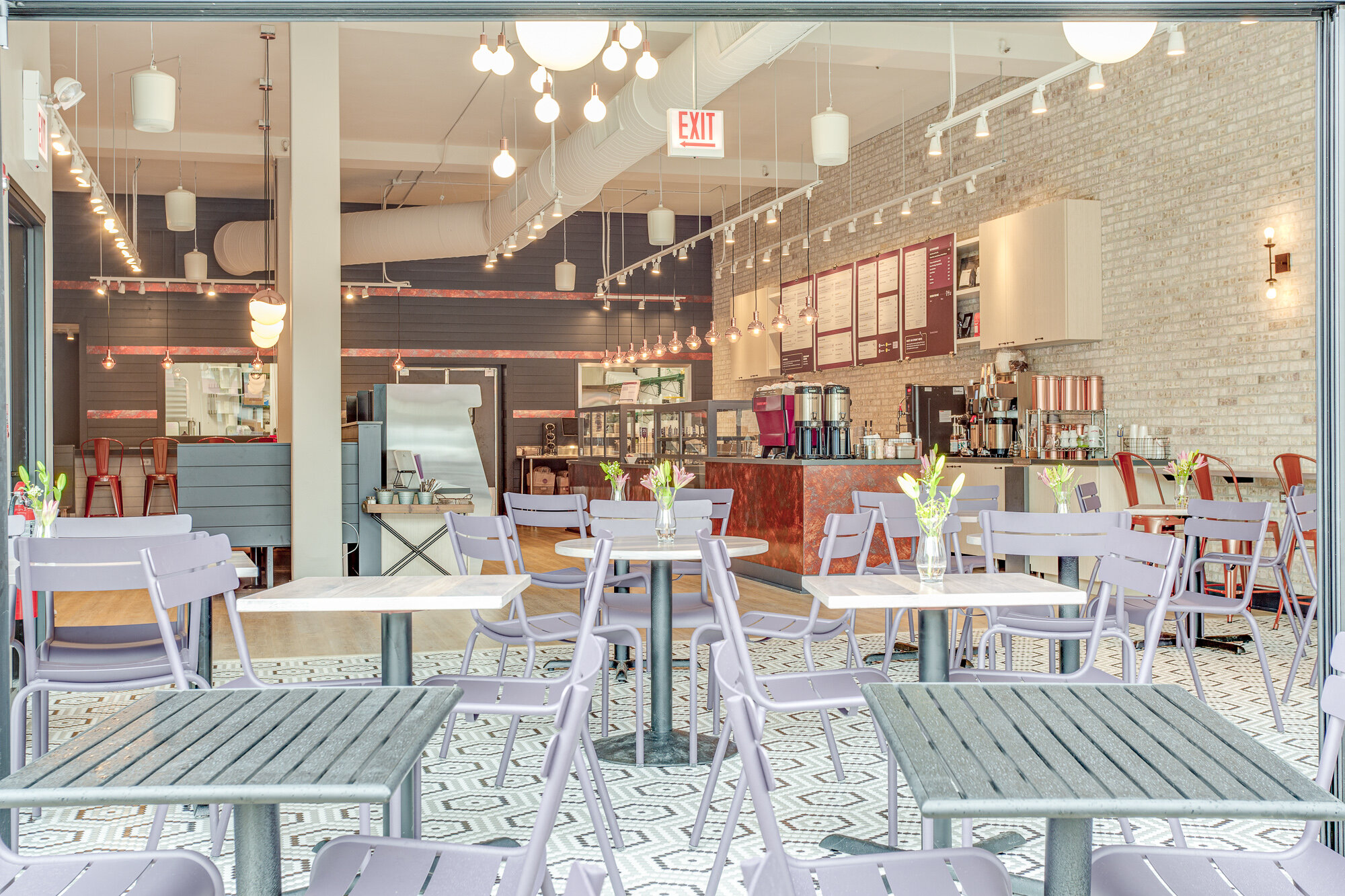 A La Grange restaurant with fresh and inviting restaurant with Ferbob furniture, a mosaic floor with hexagonal tile floor and exposed brick.